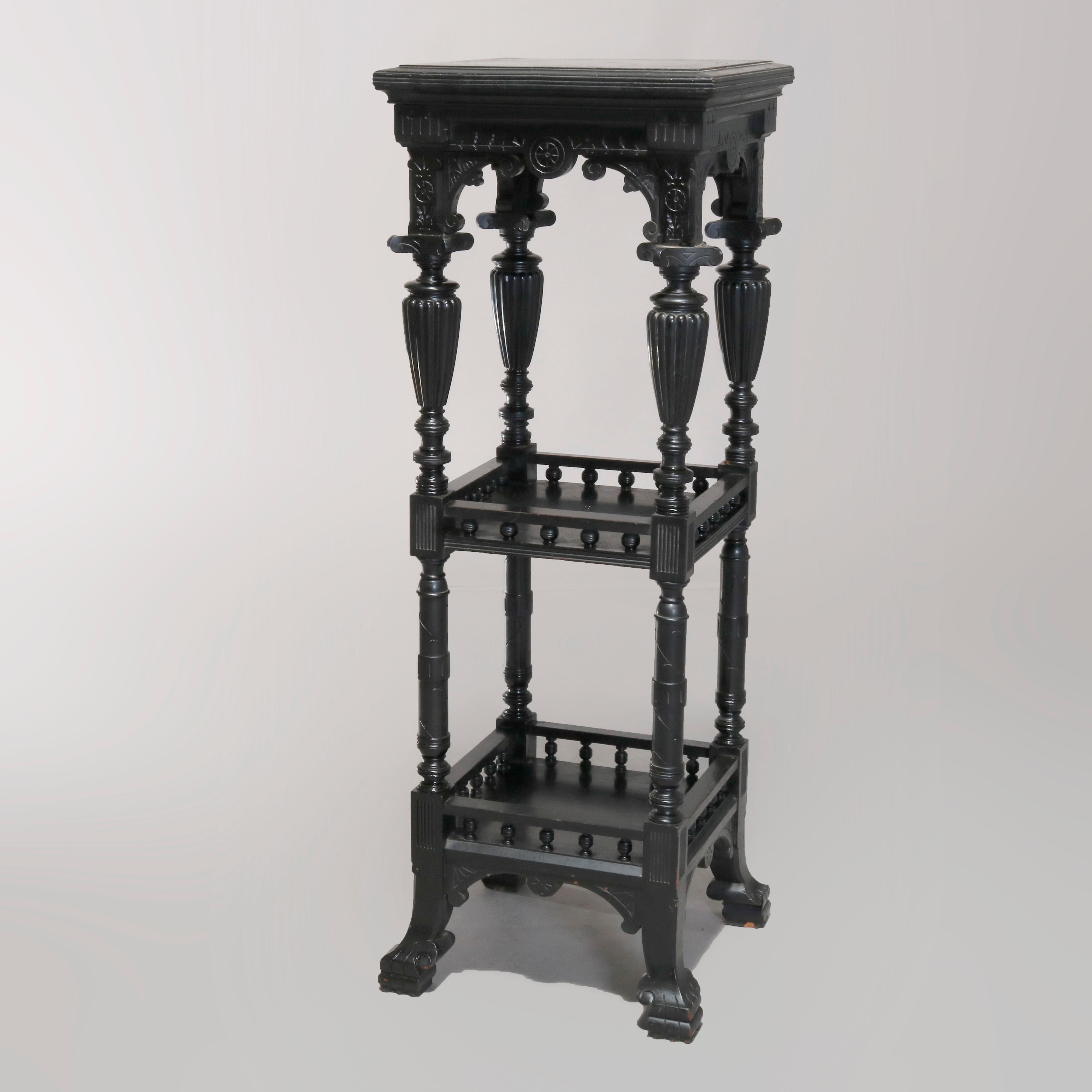 An antique Aesthetic Movement plant stand in the manner of Kimbel and Cabus offers stepped upper display surmounting shaped and foliate carved skirt raised on turned legs with urn form elements and having two shelves with stylized stick and ball