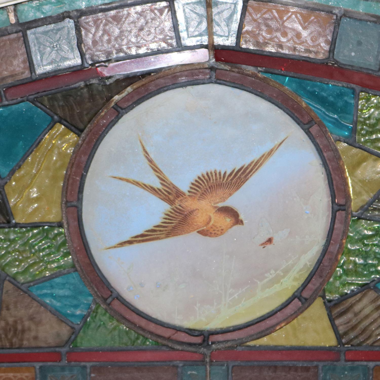 An antique Aesthetic Movement mosaic transom window features leaded stained and jeweled glass design with central medallion having hand painted bird (Swallow) and insect in flight, circa 1870

Measures: 19