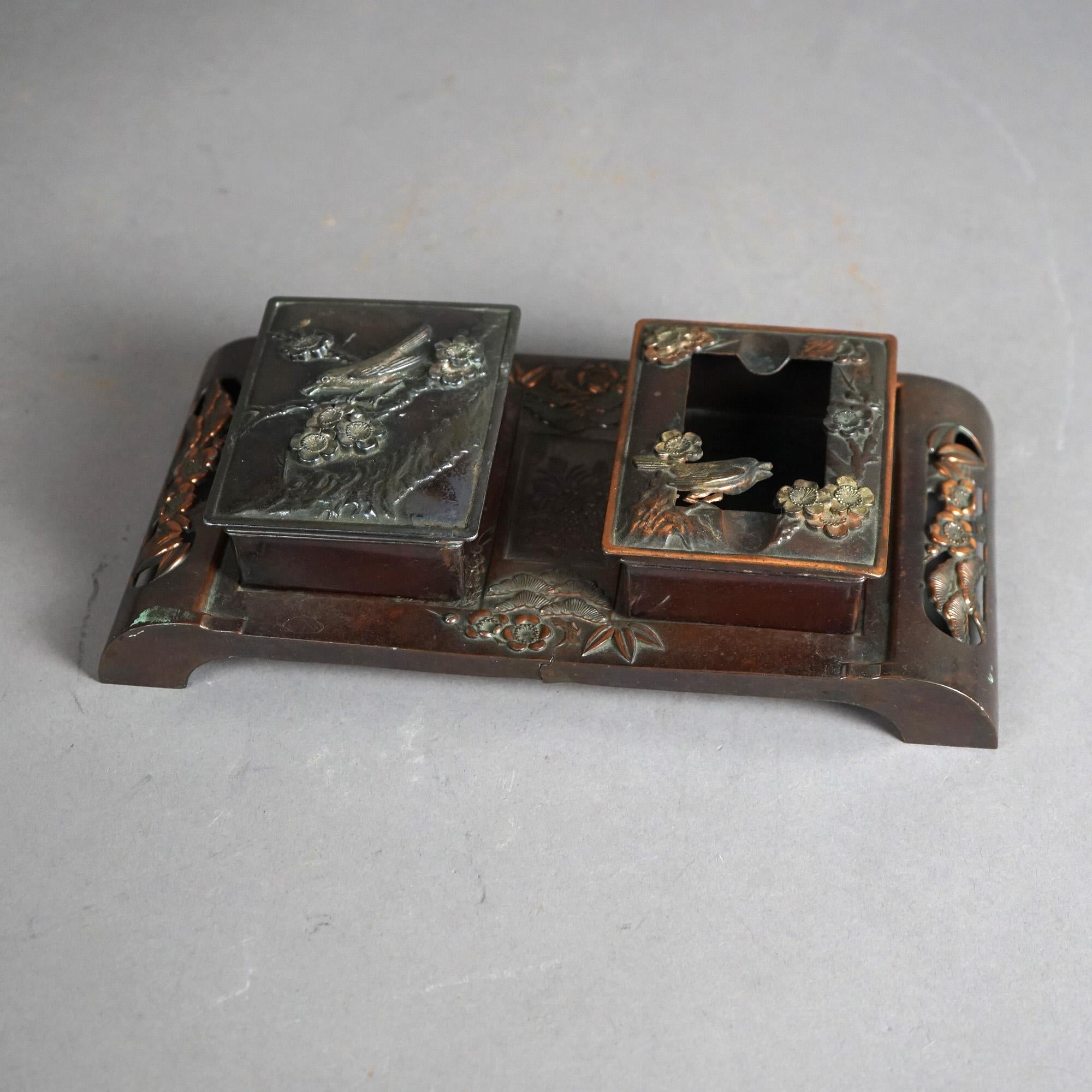 Ein antiker Schreibtisch-Organisator der Ästhetischen Bewegung bietet eine gemischte Metallkonstruktion mit zwei Boxen auf einem Tablett mit Fuß und mit geprägtem Vogel- und Blumendesign, um 1870

Maße: 2,5''H x 10,25''B x 5,25''D

Kataloghinweis: