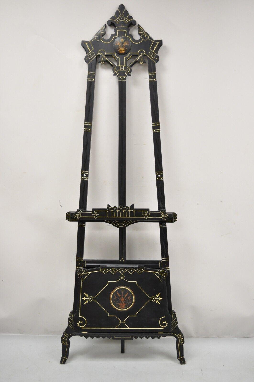 Antique Aesthetic Movement Victorian Ebonized Black Easel Art Painting stand. Item features original black ebonized finish, gold painted accents, fold out lower storage section, adjustable height easel rods, very nice antique item. Circa 19th