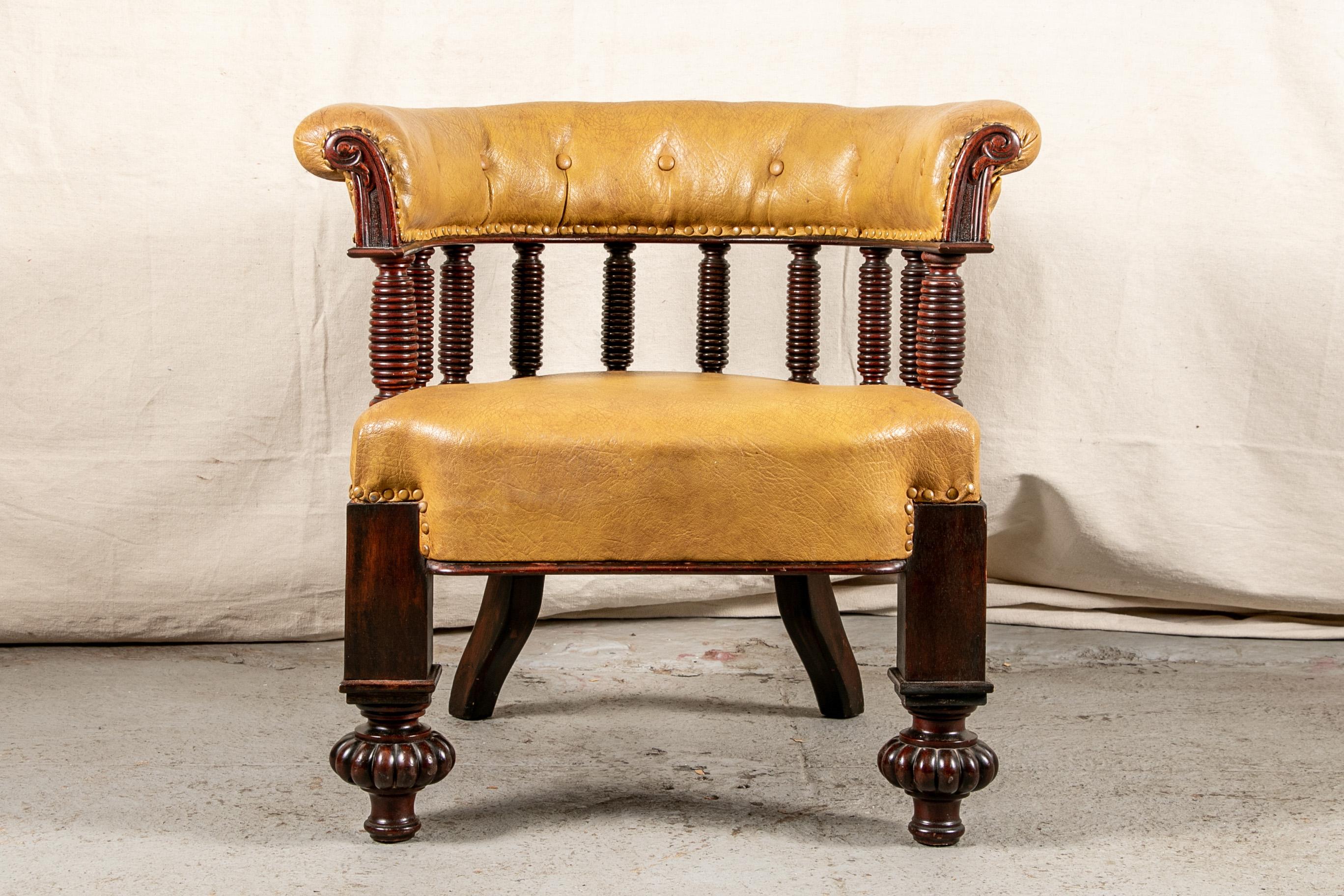 Antique aesthetic period leather library chair, tub shaped mahogany frame with multiple turned supports for the scrolled arms with tufted butterscotch tone leather upholstery with nail-head trim. The leather seat raised on block front legs with