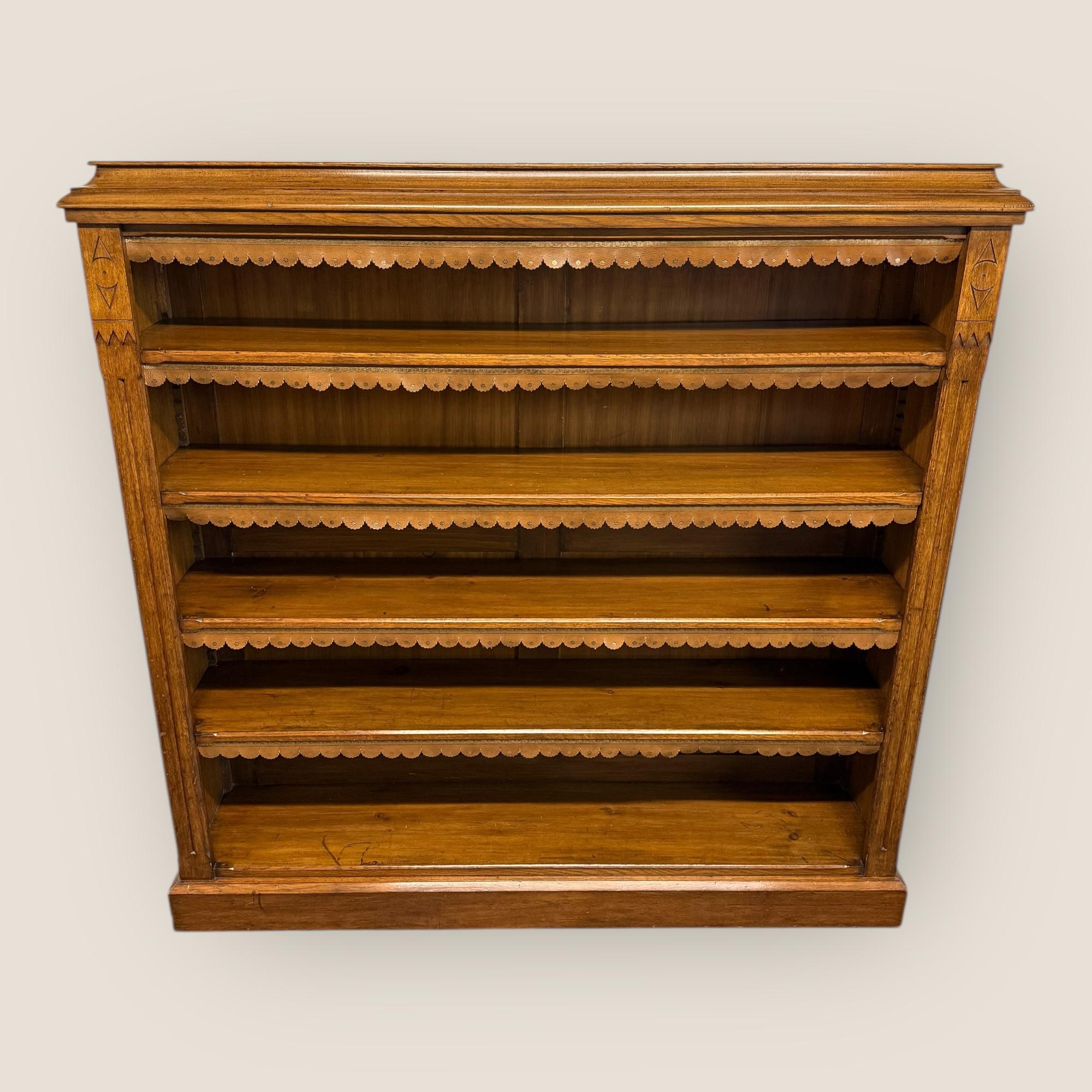 Una grande libreria a giorno in Oak Oak di epoca tardo-vittoriana (circa 1890) in stile estetico con 4 ripiani regolabili. Sotto ogni ripiano c'è una lavorazione in pelle marrone con un disegno dorato. Sulla parte superiore di ciascun lato del