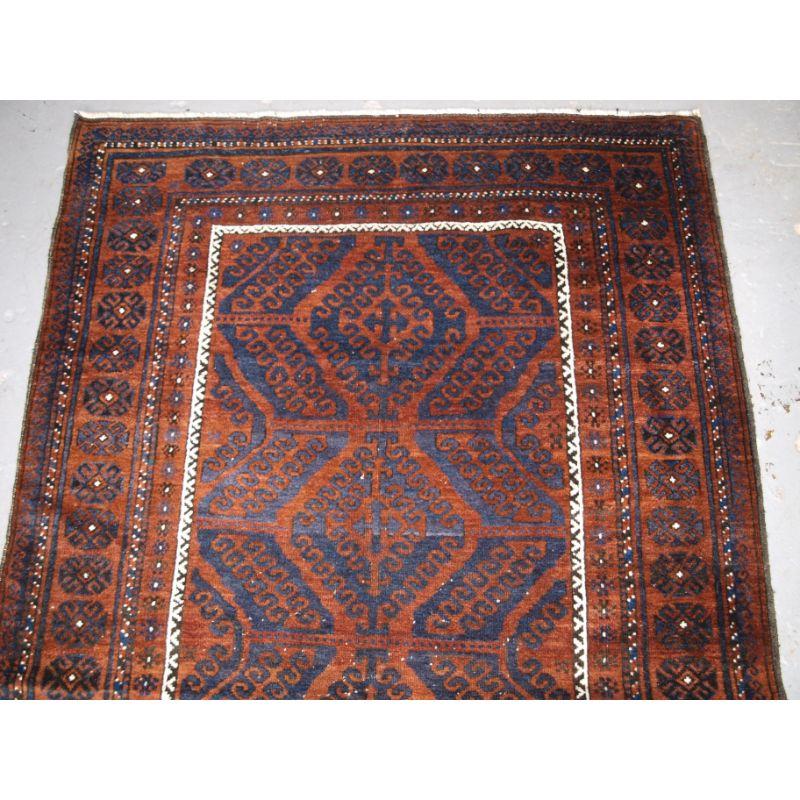 Antique Afghan Baluch rug of traditional ‘mushwani’ design, the rug is of a dark palette with warm copper coloured back ground.

Circa 1900/20.

The rug has the traditional Mushwani design is indigo blue, the design is a series of multiple latch