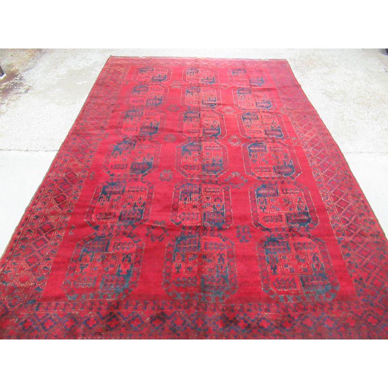 Tapis afghan ancien avec un design traditionnel Ersari, ce tapis a une superbe couleur avec un très bon champ rouge riche et chaud. Le tapis comporte trois rangées de six grandes bosses dessinées dans un bleu indigo moyen très agréable.

La moquette