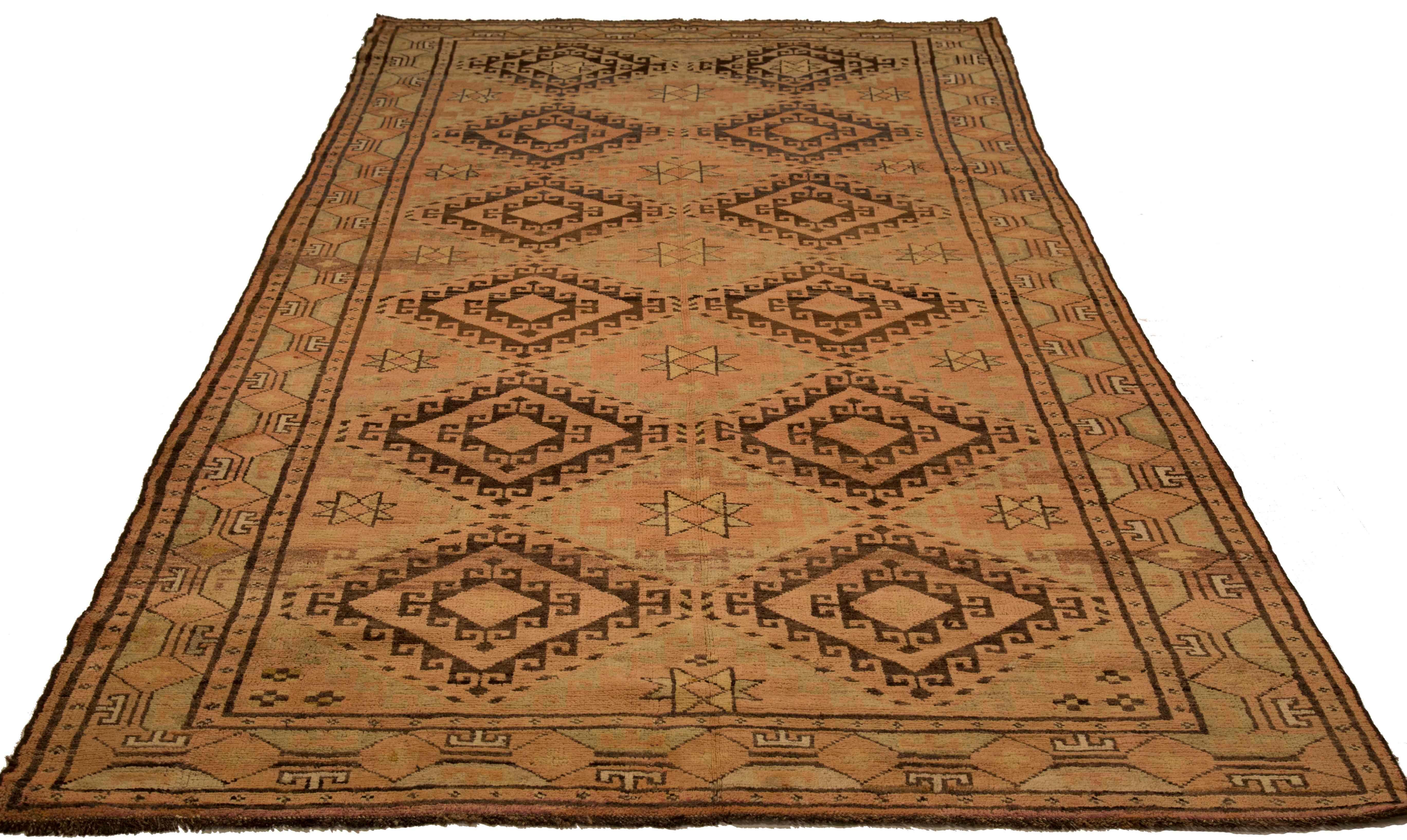 Antique Afghan area rug handwoven from the finest sheep’s wool and colored with all-natural vegetable dyes that are safe for humans and pets. It’s a traditional Afghan design featuring diamond medallions in brown and pink over a beige field. It