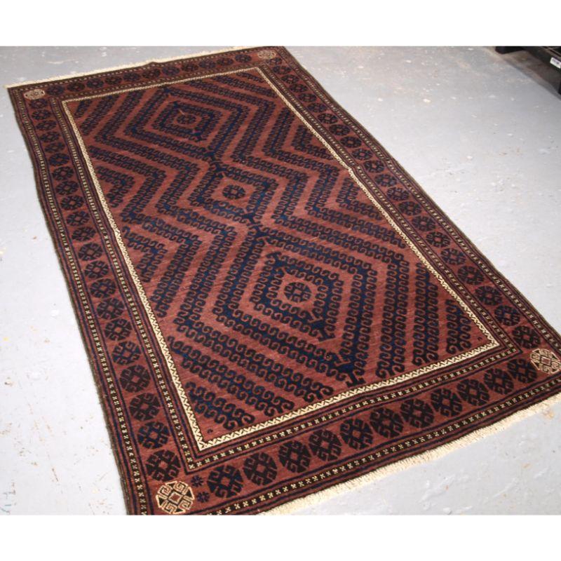 Antique Afghan Baluch rug of traditional ‘mushwani’ design, the rug is of a warm madder colour with indigo blue.

The rug has the traditional Mushwani design is indigo blue, the design is a series of multiple latch hooks or bird heads. The border