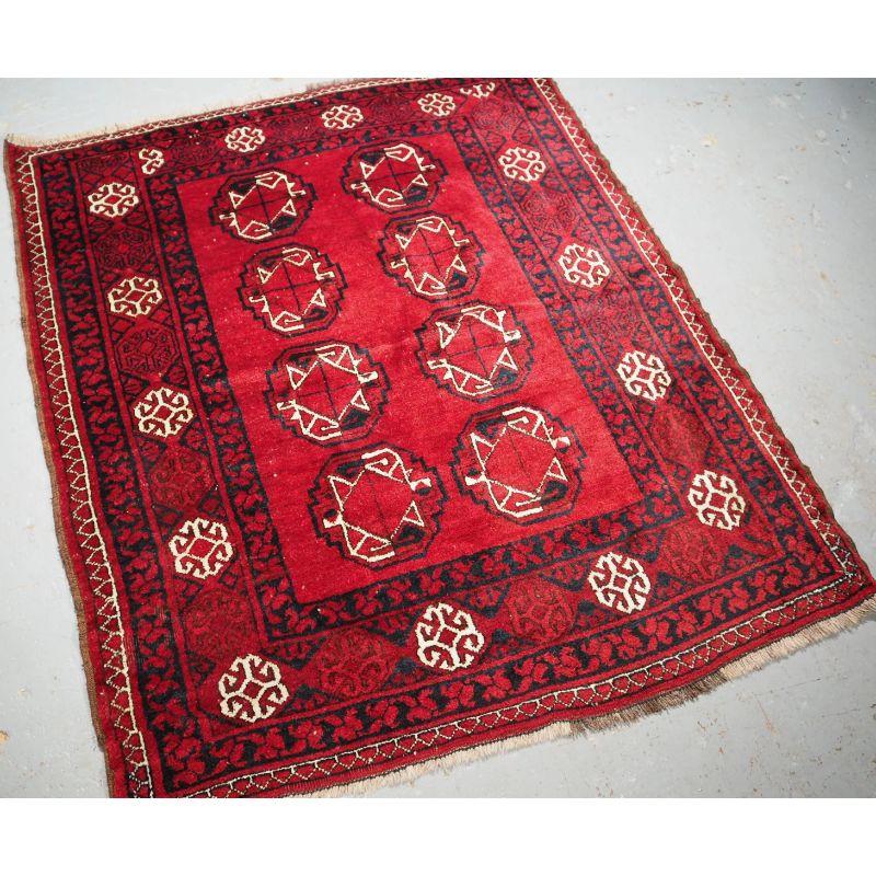 Antiker afghanischer Dorfteppich mit traditionellem Ersari-Turkmenen-Muster von kleiner quadratischer Größe.

Der Teppich hat 2 Reihen von 4 sehr großen Ersari-Turkmenen-Guls, der Teppich hat einen warmen krapproten Grund, die Bordüre ist ein