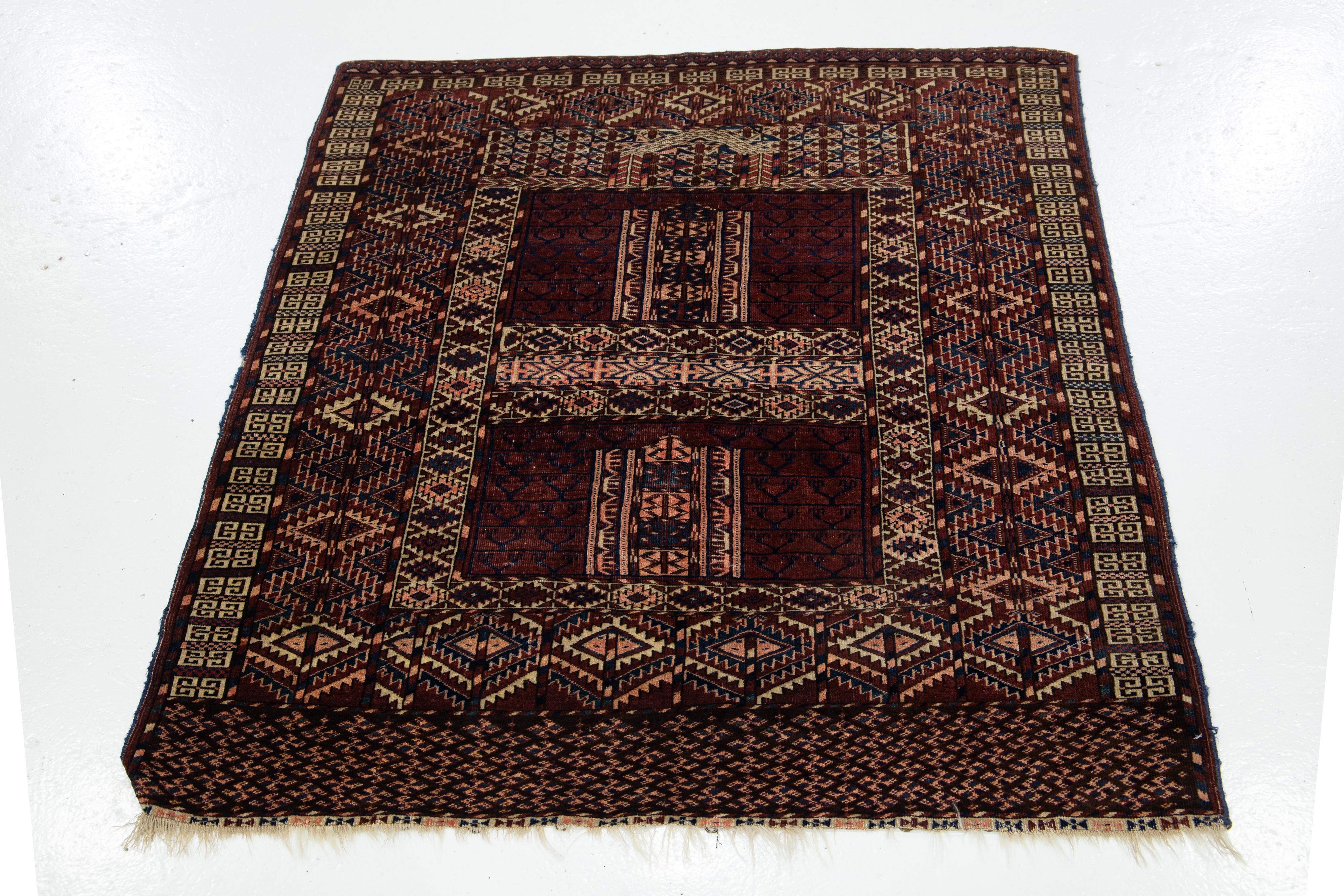 Ce tapis antique en laine Yamoud se distingue par sa couleur bordeaux et son impressionnant motif géométrique dans les tons bleu marine, pêche et beige.

Ce tapis mesure 3'11