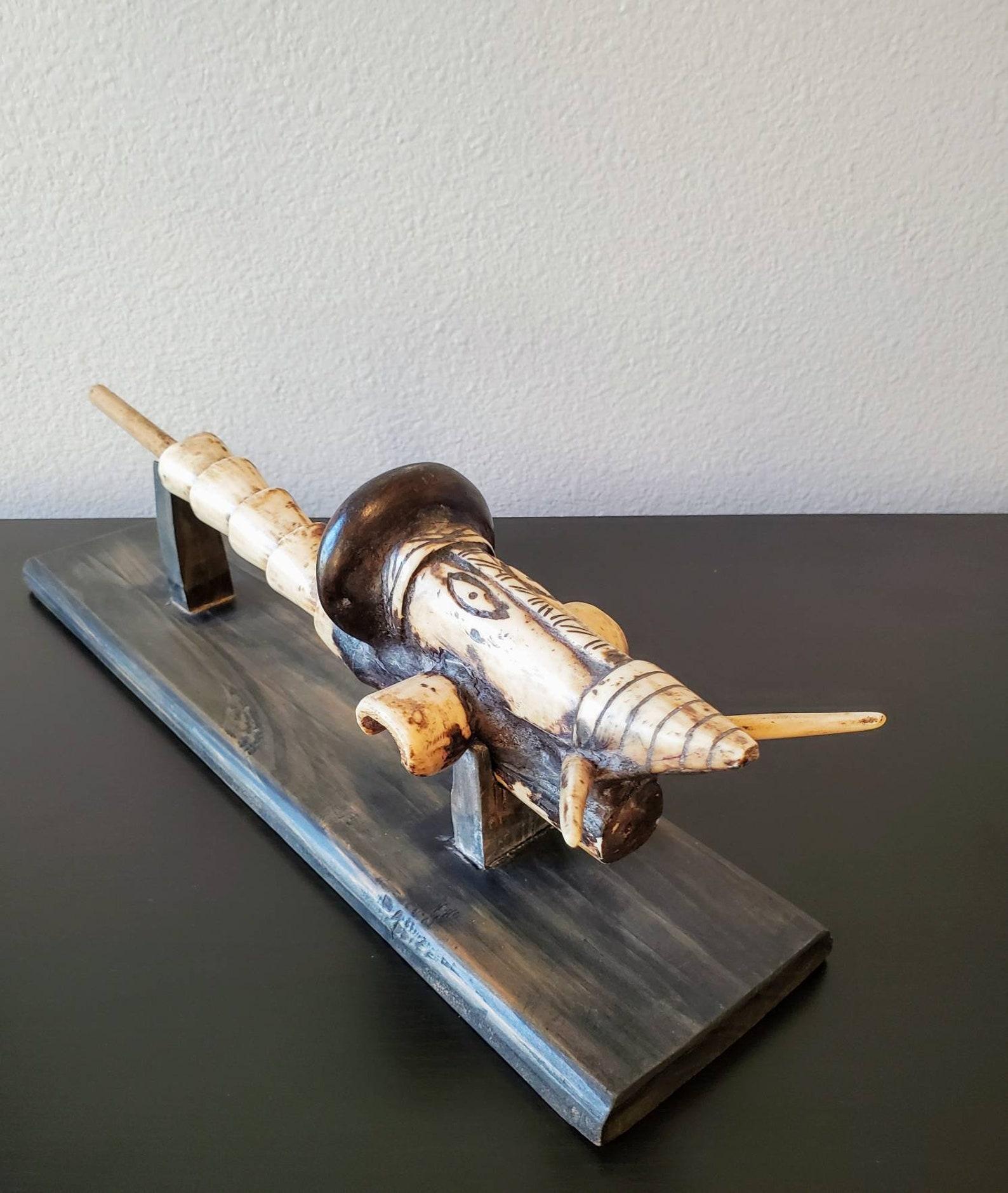 An unusual and whimsical figural TOTEM carved bone ceremonial pipe, displayed raised on a custom wooden Stand.

Outstanding patina. Superb condition. 

Dimensions: (approx)
Pipe only: 15
