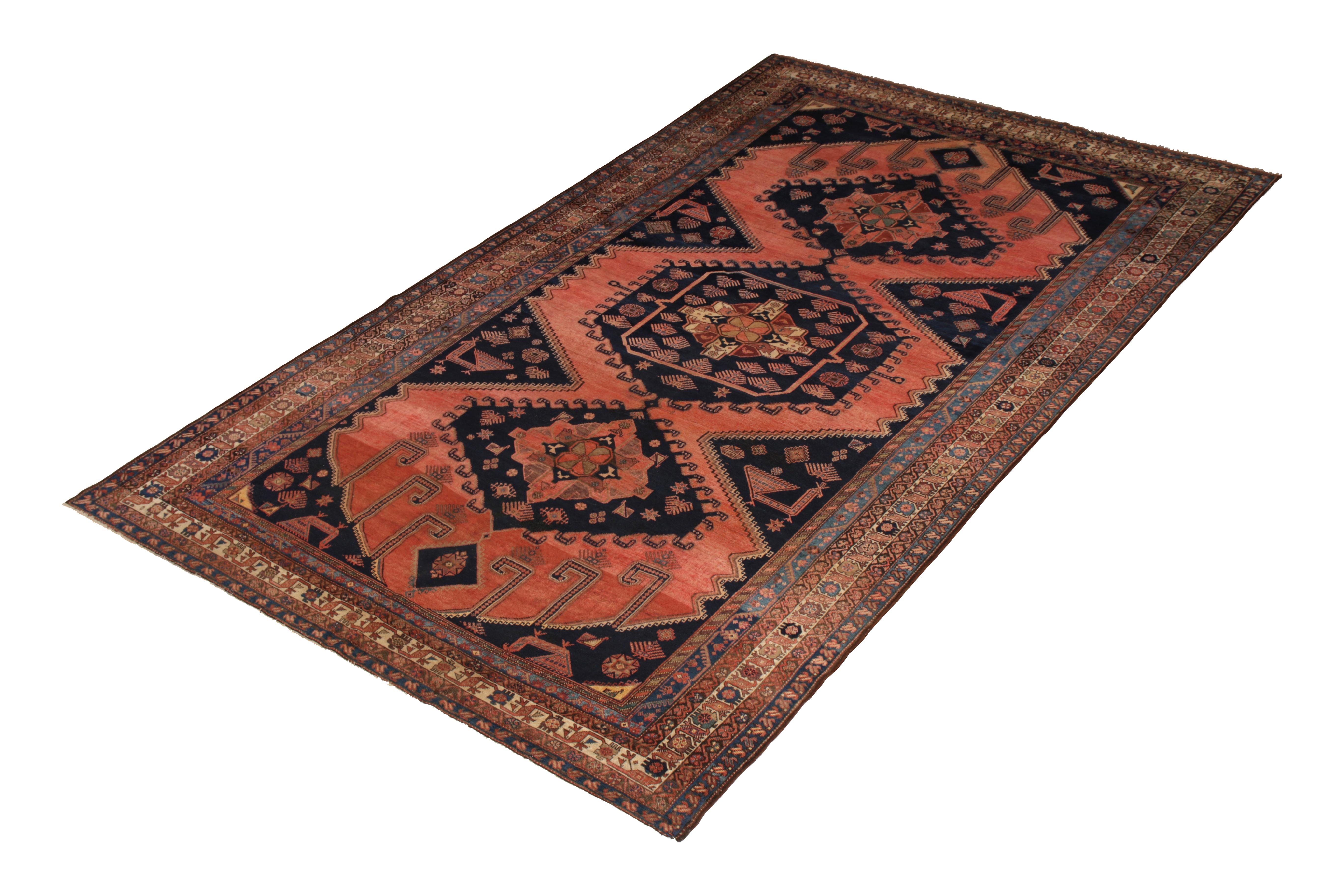 Hand knotted in wool originating from Persia circa 1890-1900, this antique Persian rug connotes an Afshar rug design, enjoying a distinctive coral-red colorway juxtaposed beautifully with the navy blue background notes. The subtle abrash complements
