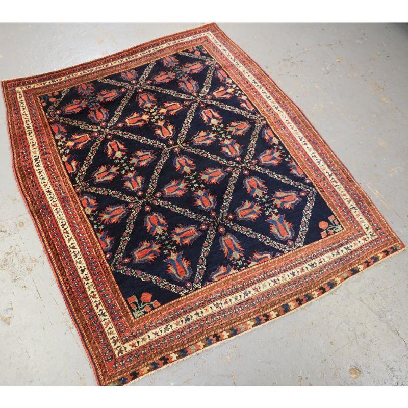 Antique Afshar tribal rug with lattice and flowering tulip design.

A very sweet rug of small square size, the colourful tulip flowers stand out against the dark indigo blue ground. The borders are of classic Afshar design.

The rug is in very good