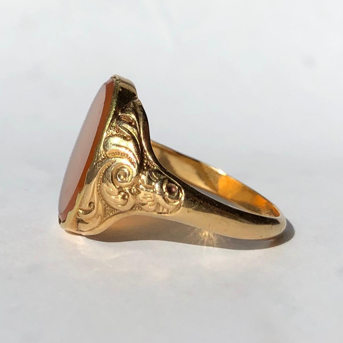 This ornate ring holds an oval agate stone which is a gorgeous amber colour and has flecks of deep red. The shoulders have a stunning moulded scroll and floral design. The stone is set within the 9ct gold. 

Ring Size: R or 8 1/2 
Stone Dimensions: