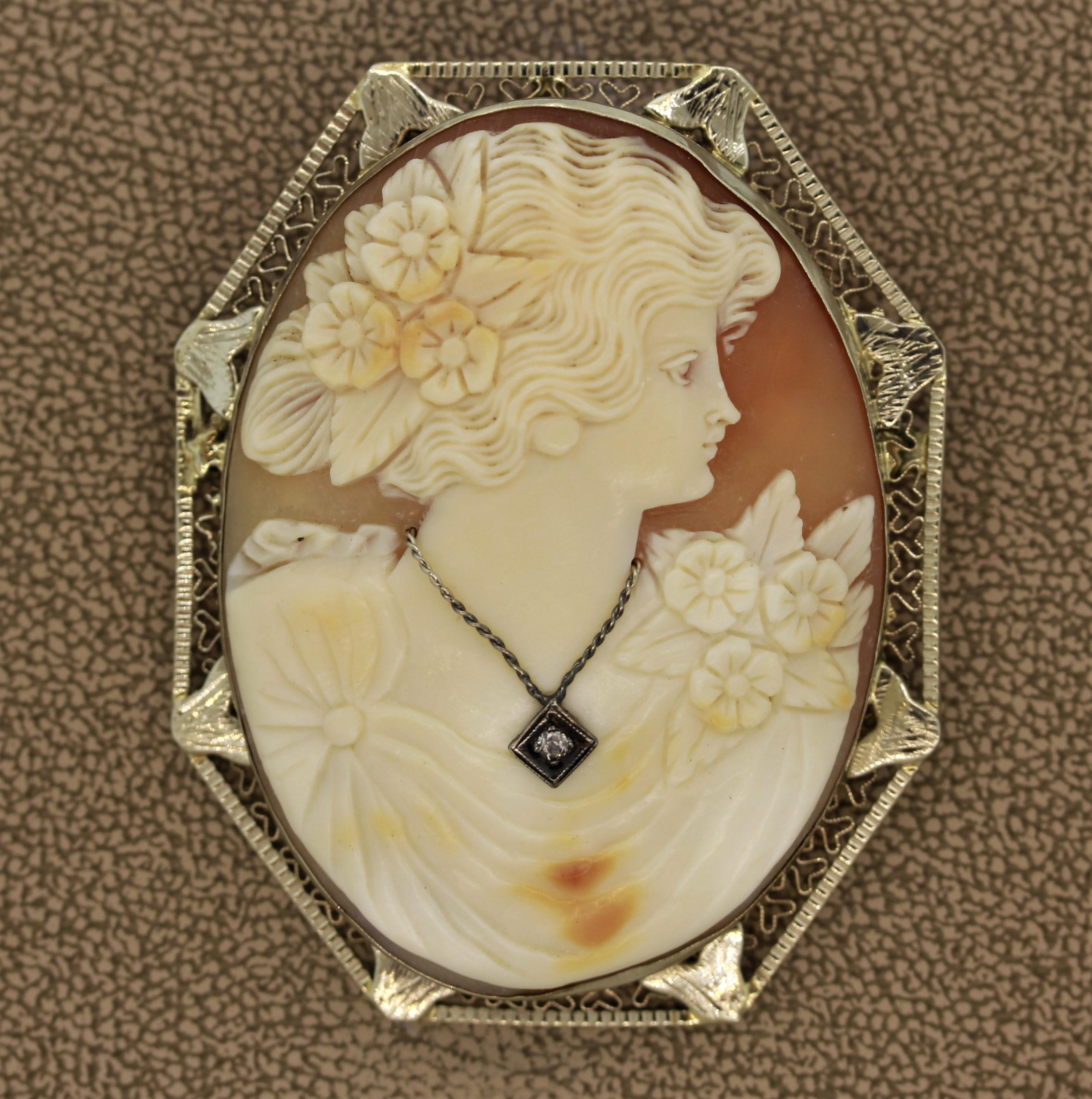 A large antique cameo depicting a noble woman dressed in a beautiful gown with flowers in her hair. She is wearing a necklace which has a round cut diamond set in it. The frame is made in 14k white gold. Can be worn as a brooch or pendant.

Length: