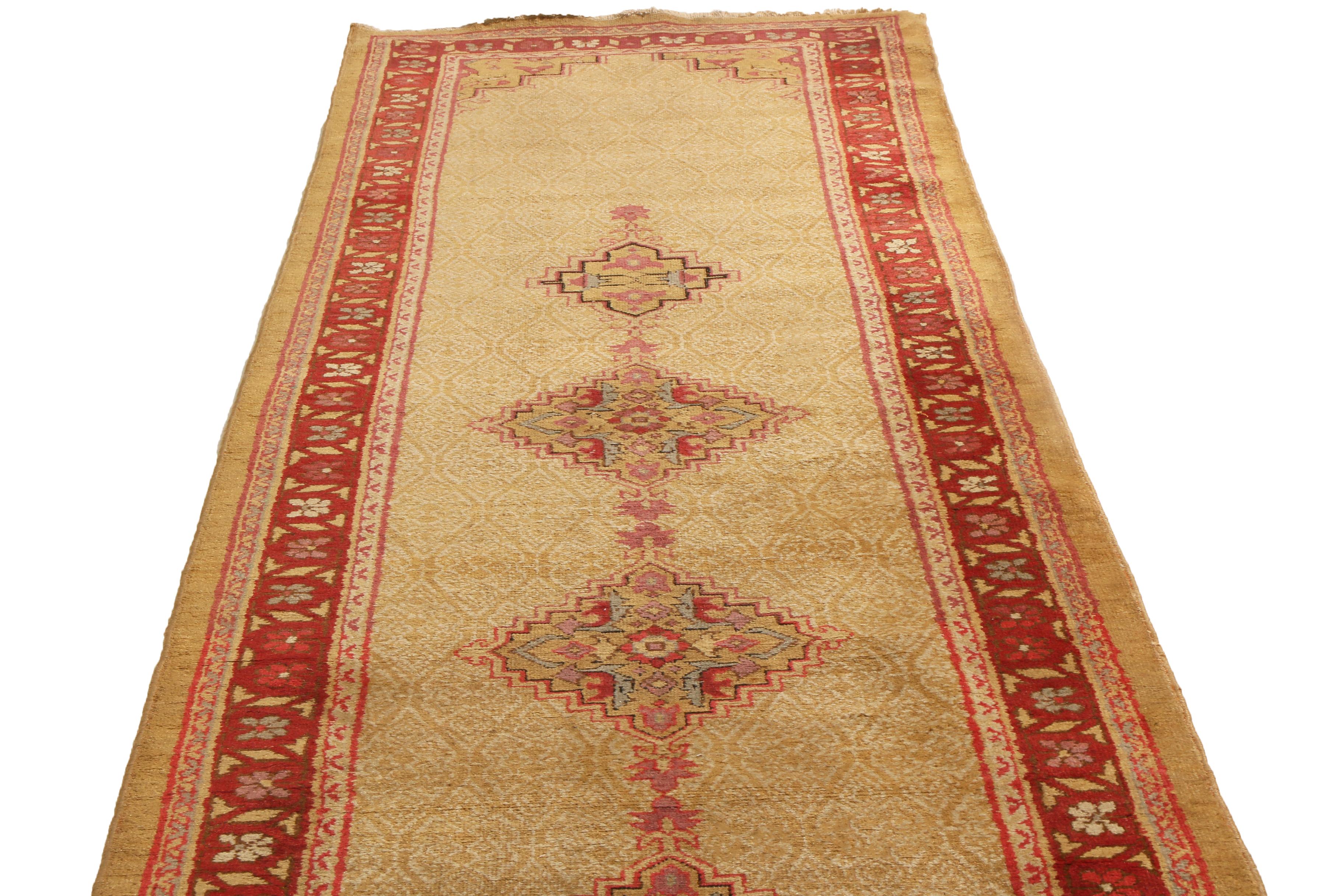 Originating from India in 1890, this antique Agra runner enjoys a rich central border in burgundy and blue color ways accenting the beige and pink field and medallions throughout. Hand knotted in a durable wool pile, the expansive medallion field