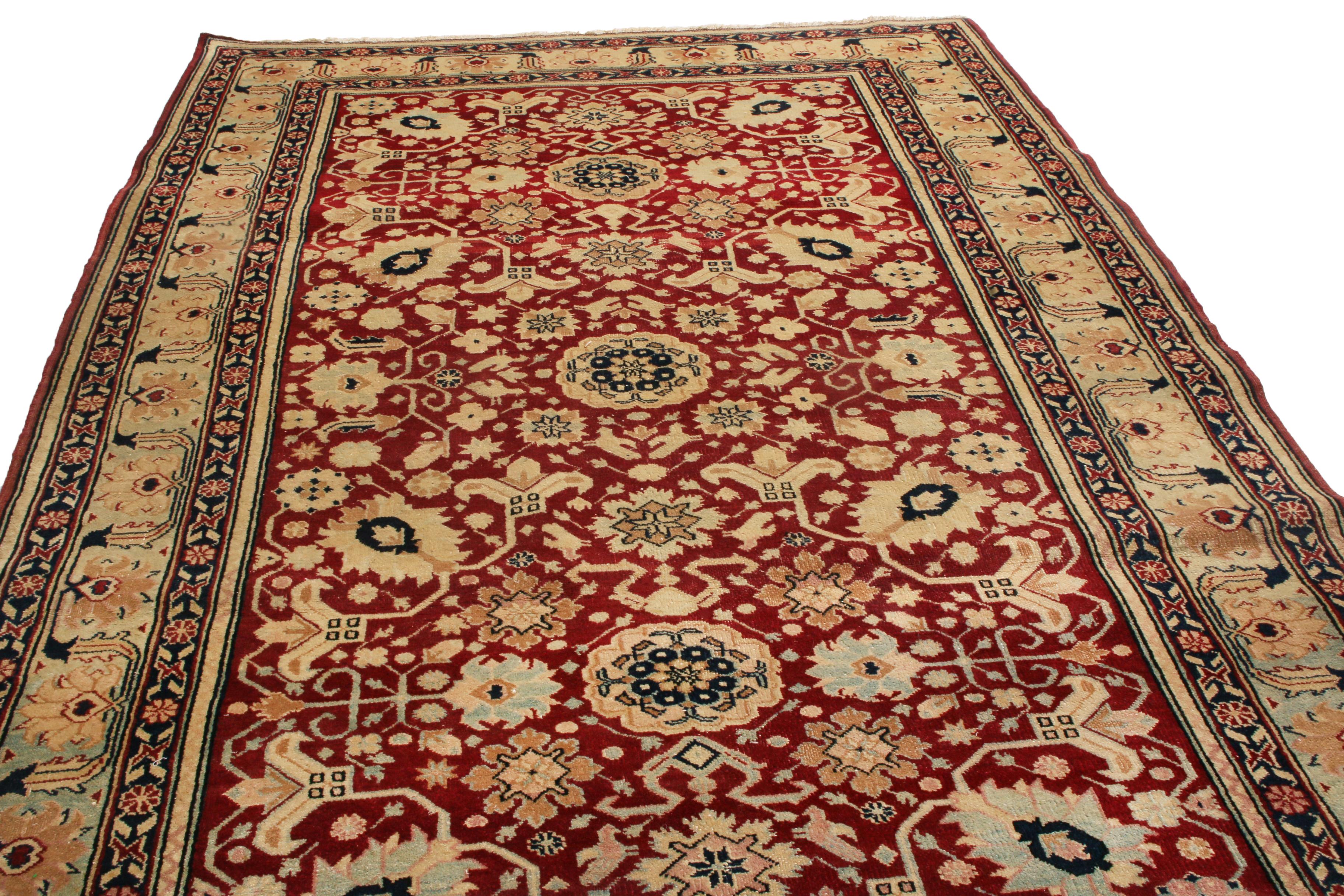 Hand knotted in India originating between 1900-1910, this antique Agra wool rug enjoys a rare bright green colorway in the border, complemented by the classically rich autumnal burgundy and beige-gold hues. A marriage of intricacy and gentility, the