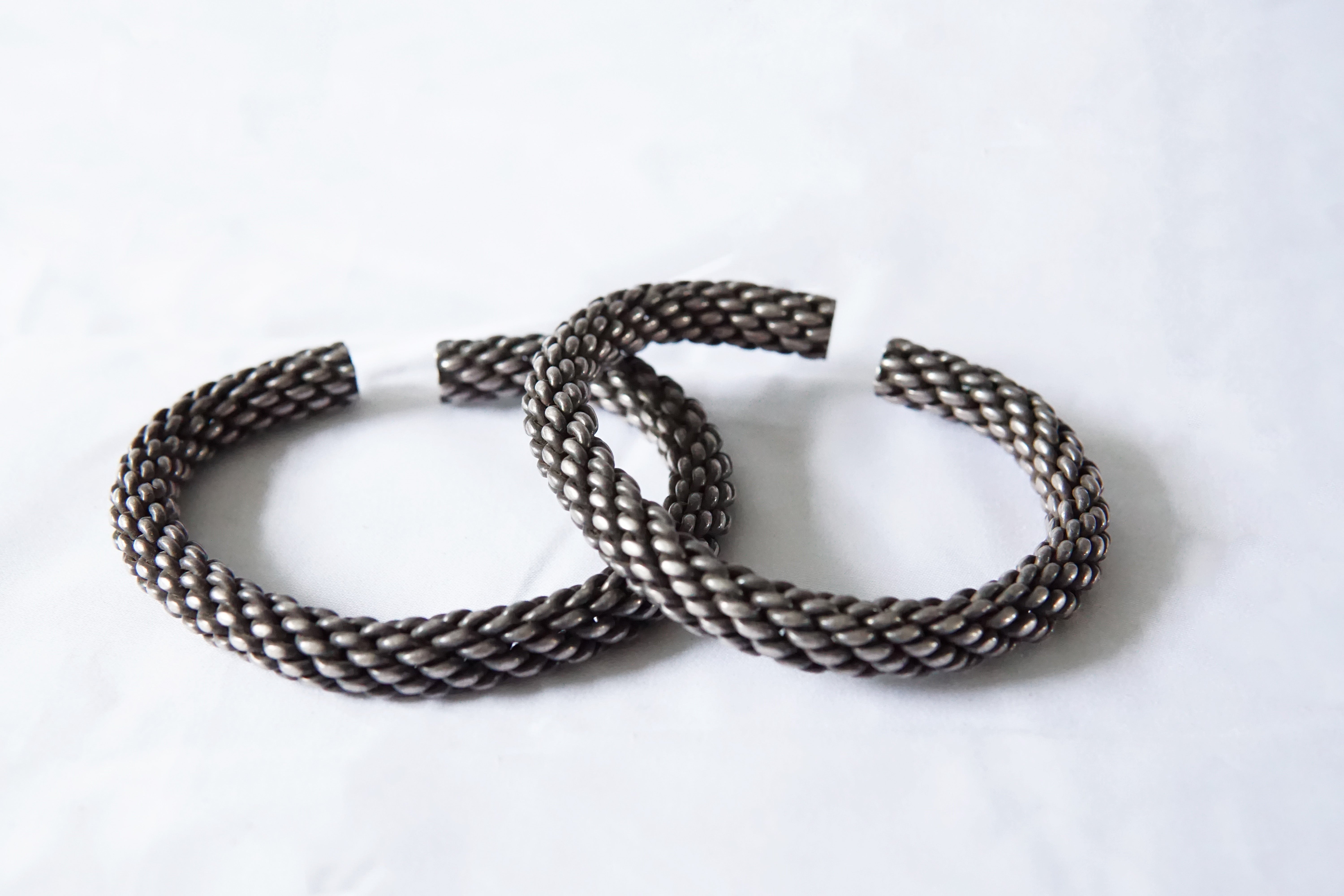 This pair of Akha tribe bracelets are smaller and thinner than the majority of Akha woven silver bracelets encompassing this spiral design, the Akha tribe lives on the hills bordering Laos, Thailand, and Burma. Despite the size, they are