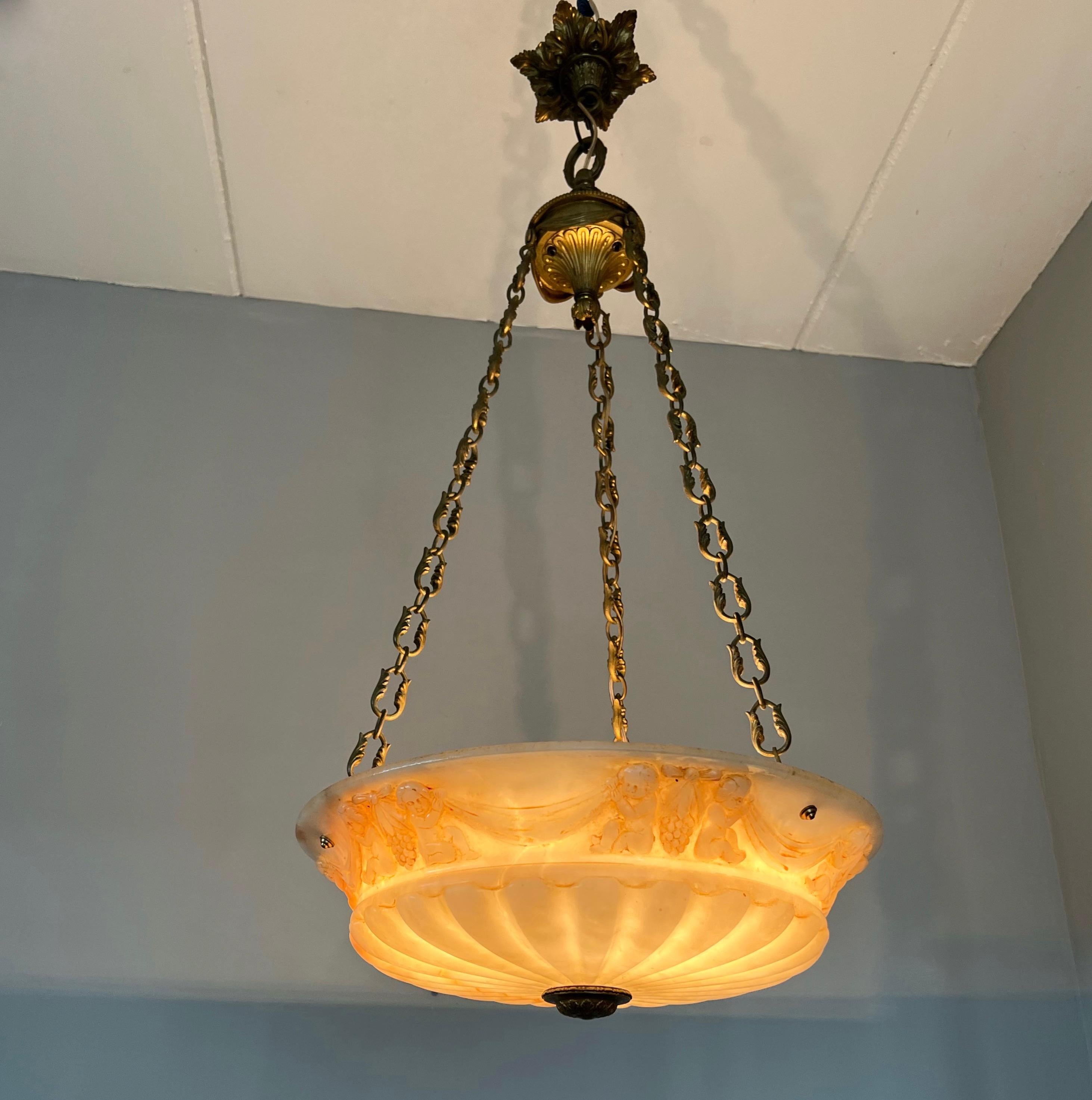 Large early 1900s handcrafted, natural mineral stone with bronze hardware light fixture.

It is difficult to understand how they created such a perfect, circular shape pendant out of one solid alabaster rock and also make such fine carvings in