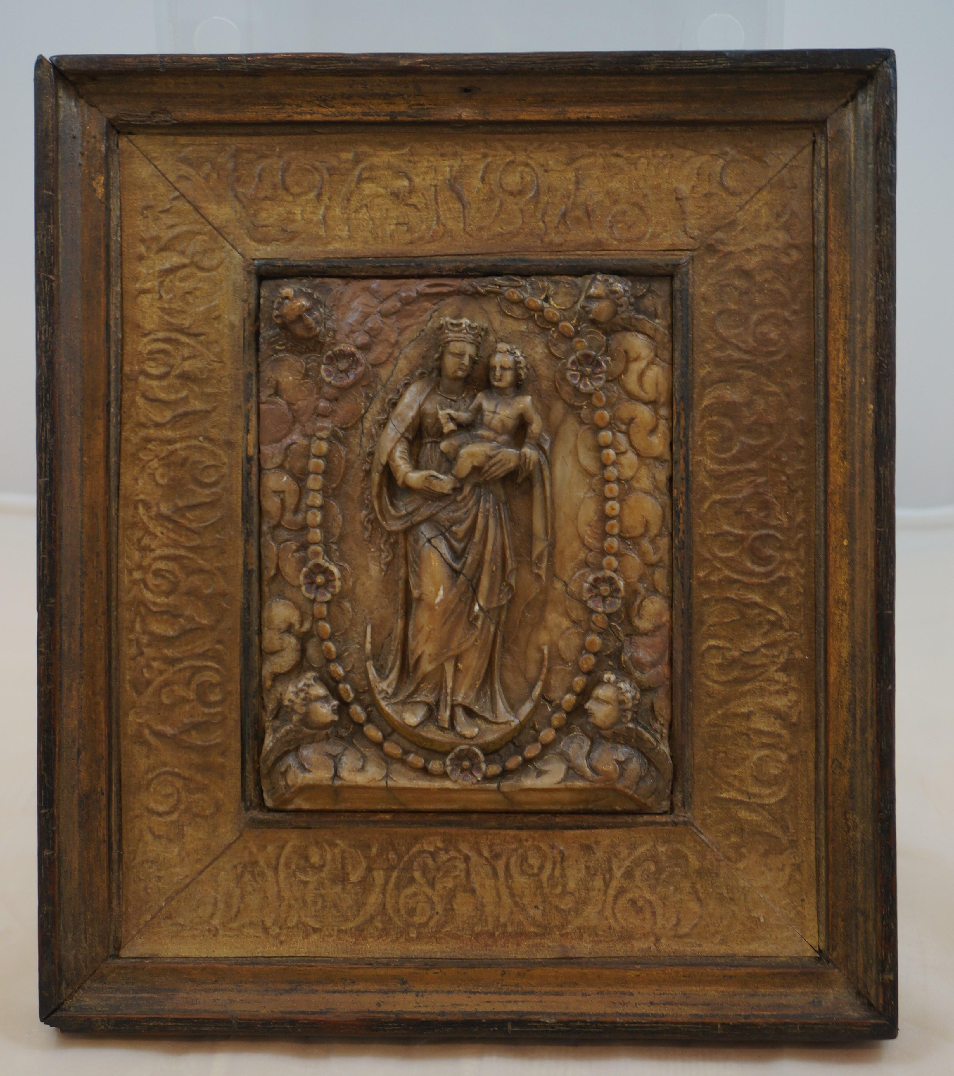 Alabaster Plaque depicting Saint Mary with a crown and standing on a crescent moon holding the infant Jesus and surrounded by a Rosary with 5 roses and 4 Cherubs (angels) and clouds.

This plaque is made in Mechelen (Malines) a central Belgian city