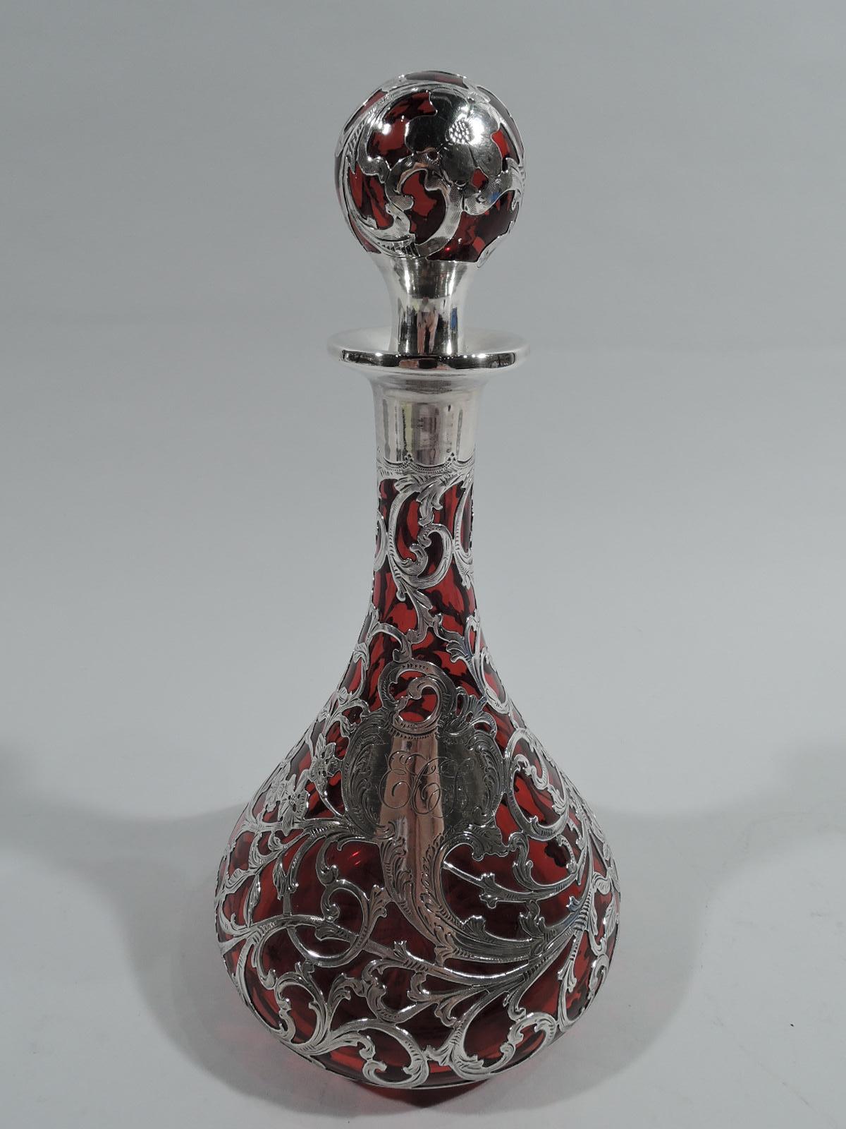 Turn-of-the-century Art Nouveau glass decanter with engraved silver overlay. Made by Alvin in Providence. Conical bowl and cylindrical neck with everted rim. Star cut to underside. Ball stopper with spool neck. Dense and entwined flowering