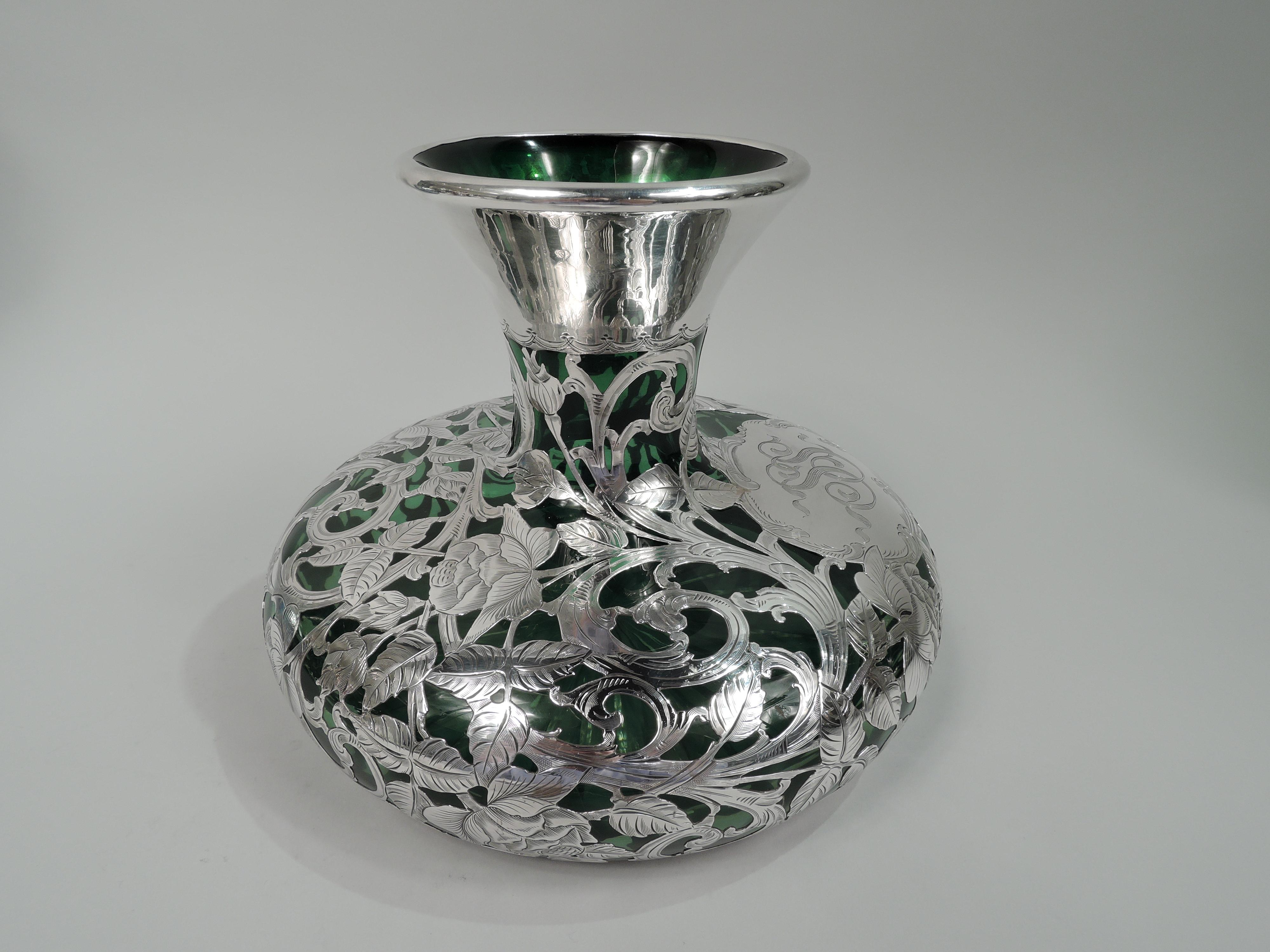 Turn-of-the-century Art Nouveau glass vase with engraved silver overlay. Made by Alvin in Providence. Tapering neck with bellied bowl. Overlay in form of entwined and tentacular tendrils. Glass is green. Silver marked including maker’s stamp and no.