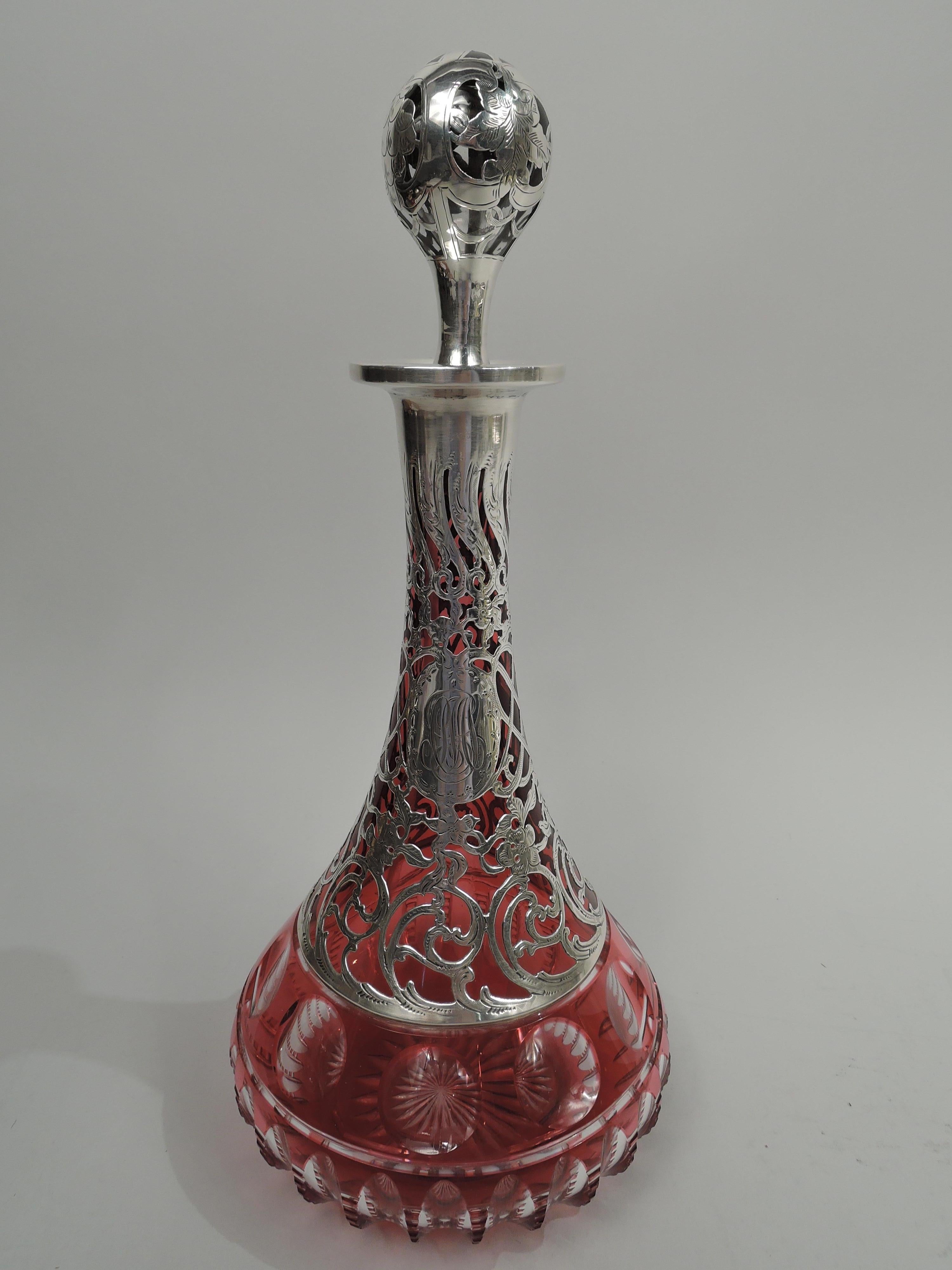 Art Nouveau glass decanter with engraved silver overlay. Made by Alvin Corporation in Providence, circa 1890. Conical with cut-to-clear geometric ornament at base, and star on underside. Dense overlay with rinceaux, flowers, and scrollwork. Ball