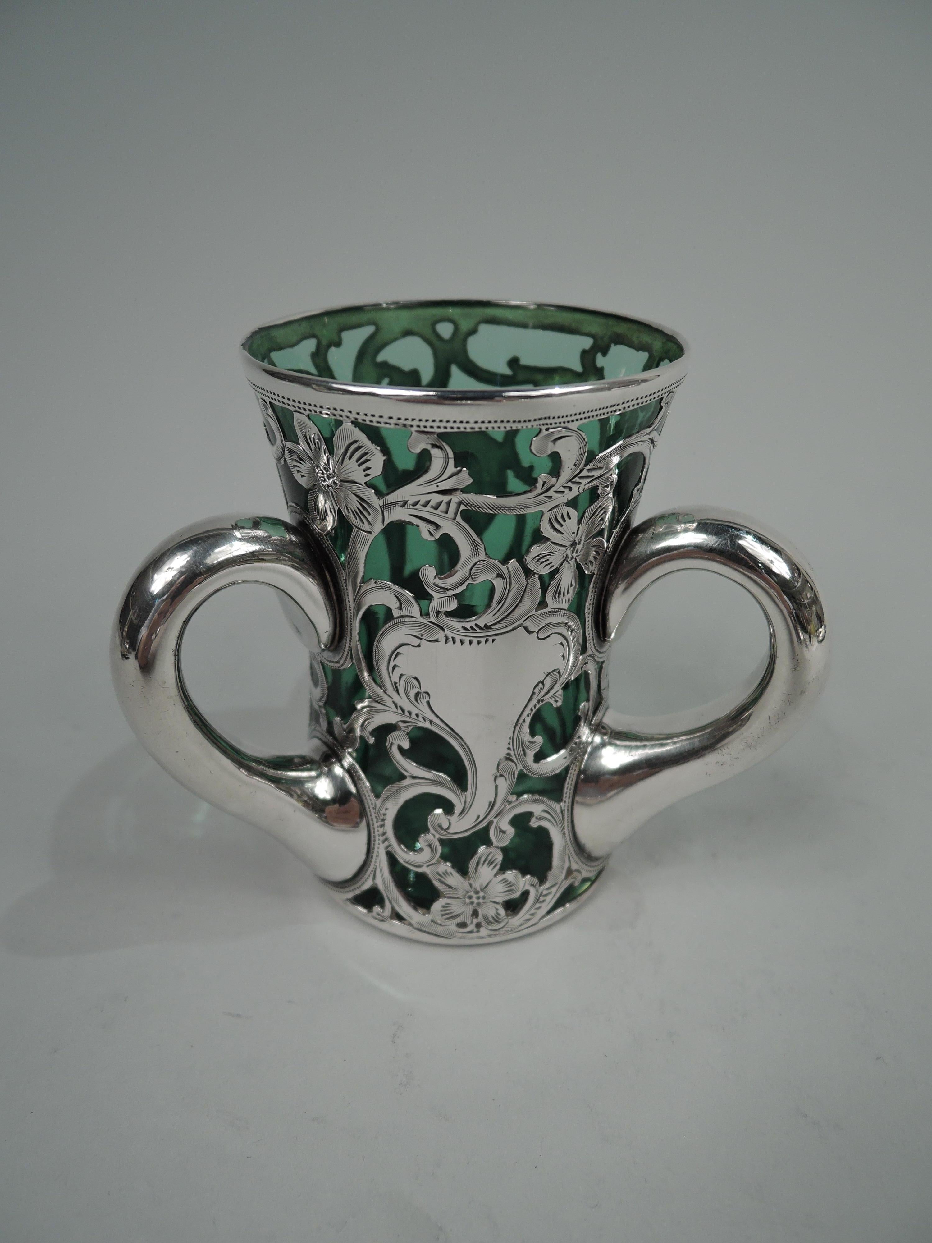 Art Nouveau glass vase with engraved silver overlay, ca 1900. Made by Alvin in Providence. Gently flared cylinder. Overlay in form of dense and entwined leafing scrolls and flowers. Asymmetrical scrolled cartouche (vacant). Three collared scroll