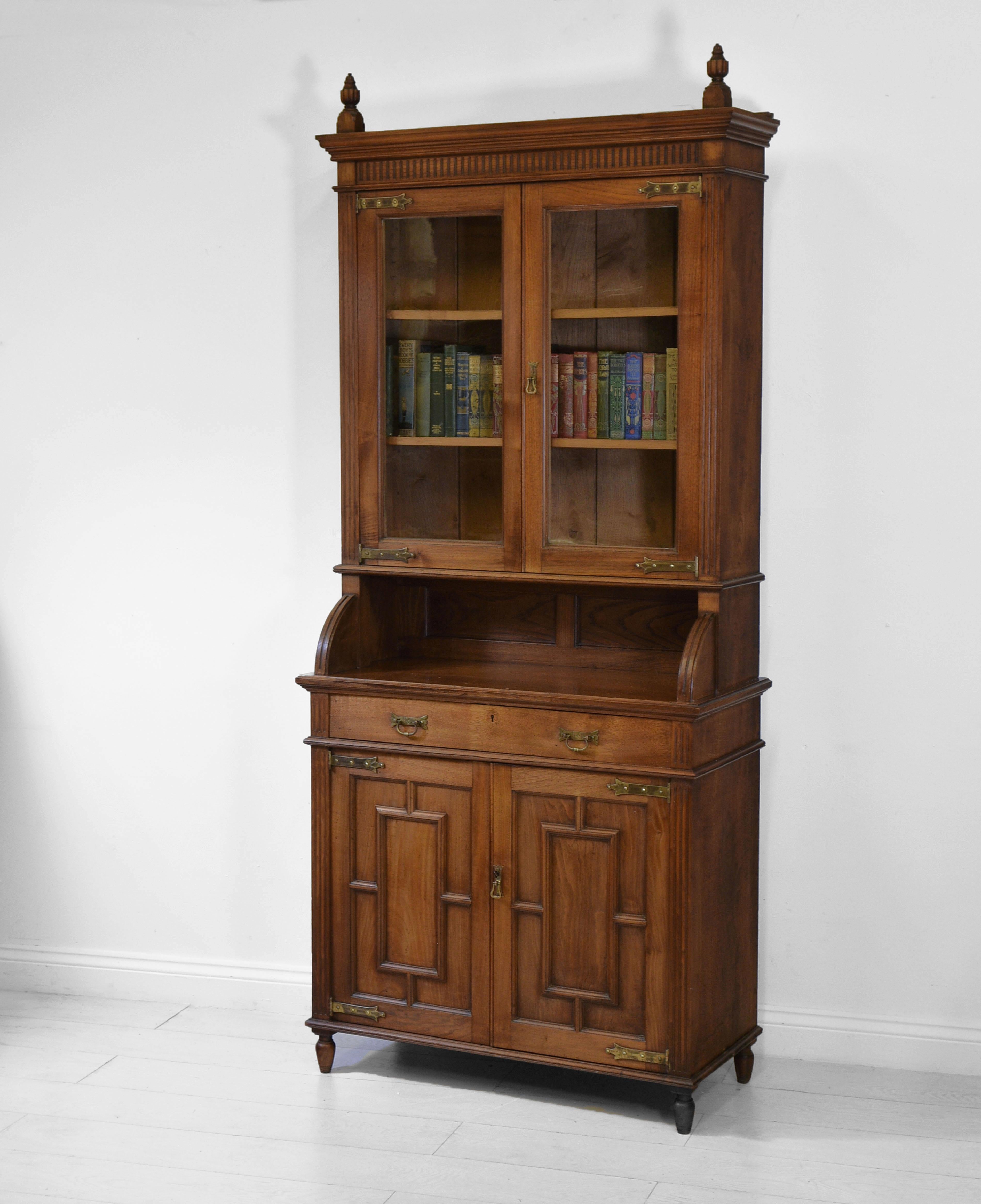 An American Aesthetic Movement chestnut tall bookcase cabinet with brass stylised hinges and turned finials. Circa 1880.

The Aesthetic Movement started in England in the late 1860's. Its popularity spread to the United States from the mid 1870's