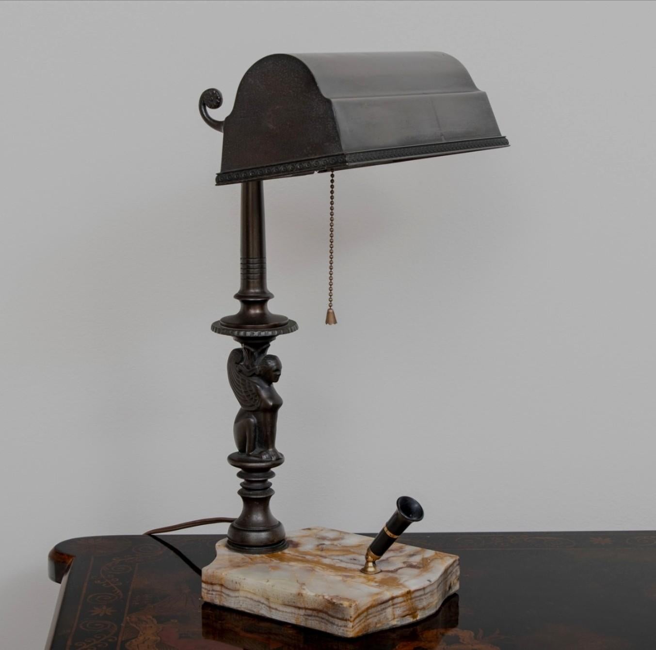 A fine antique American Art Deco Amronlite Sheaffer Fountain Pen banker's style desk lamp deluxe, circa late 1920s, featuring beautifully patinated original brass shade, rising on figural Egyptian winged sphinx form column on a shaped marble base