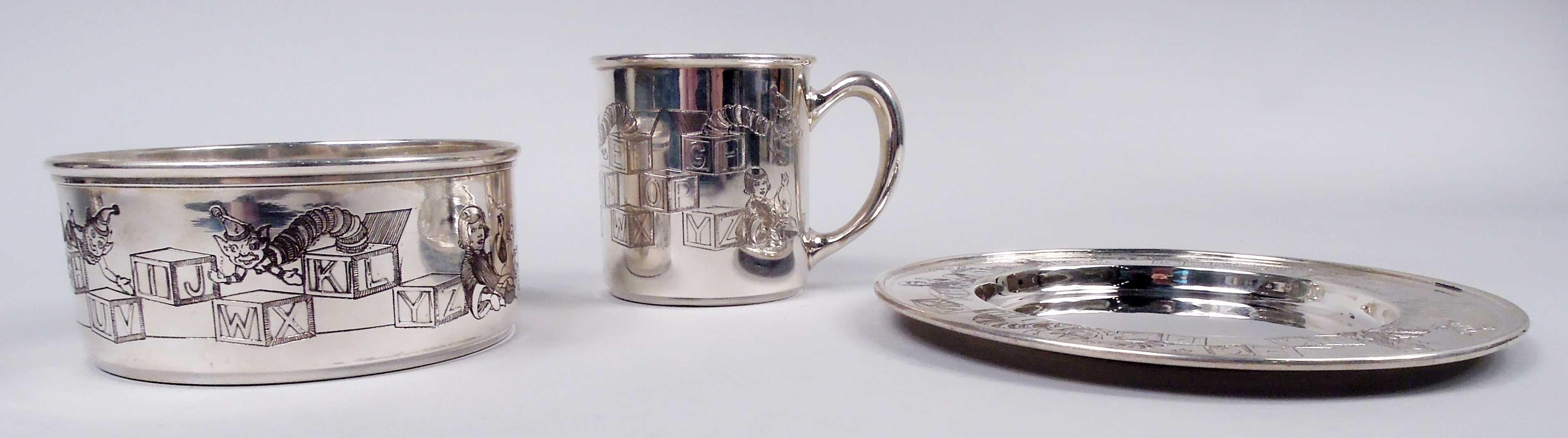 Art Deco sterling silver 3-piece baby set, comprising mug, bowl, and plate, ca 1920. Mug and bowl have straights sides; plate has plain and deep well. Bobbed and ringleted girls lean against stacks of ABC blocks. some with springing jacks. All
