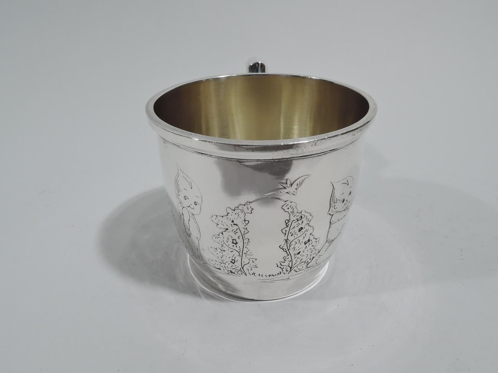 Art Deco sterling silver baby cup, circa 1920. Gently curved and tapering sides with scroll bracket handle. Acid-etched frieze with stubby-legged toddlers exploring the shrubbery. Arbor has vacant center for engraving. Interior gilt washed. Fully
