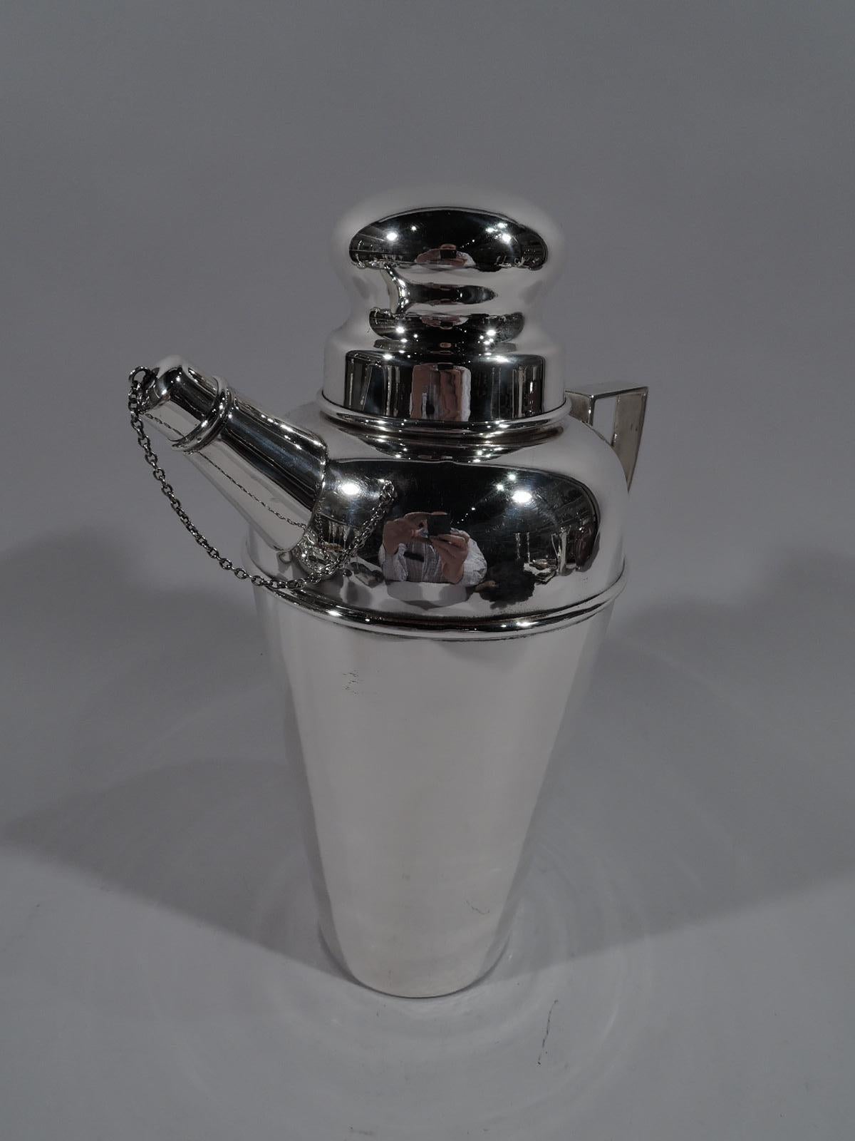 American Art Deco sterling silver cocktail Shaker, circa 1925. Straight and tapering bowl, curved shoulder, short inset neck, and sleek scroll-bracket handle. Bun cover and stubby diagonal spout with chained cap. Cover and chain fit snuggly. Marked