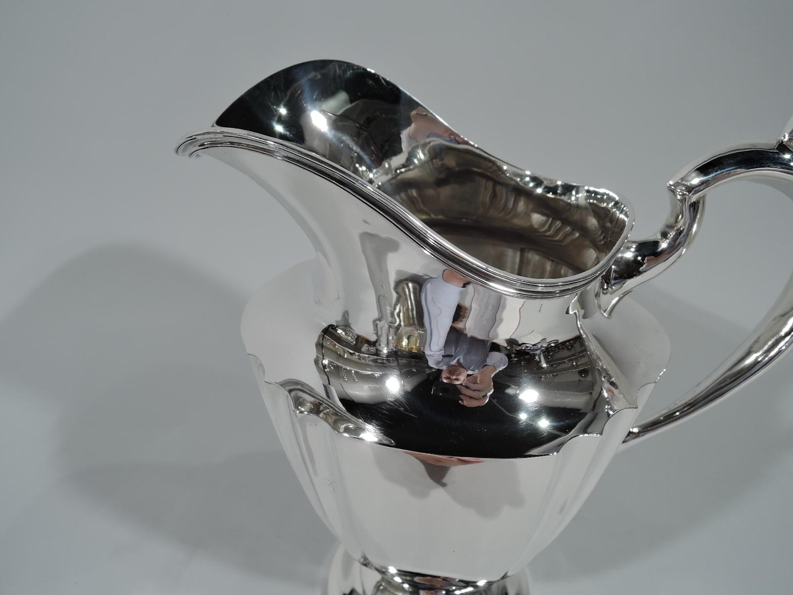 American Art Deco sterling silver water pitcher, circa 1925. Ovoid and tapering body with 4 clusters of fluting. Capped high-looping handle, helmet mouth with reeded rim, and stepped domed foot. Hallmarked “Sterling 0911”. Weight: 21.4 troy ounces.