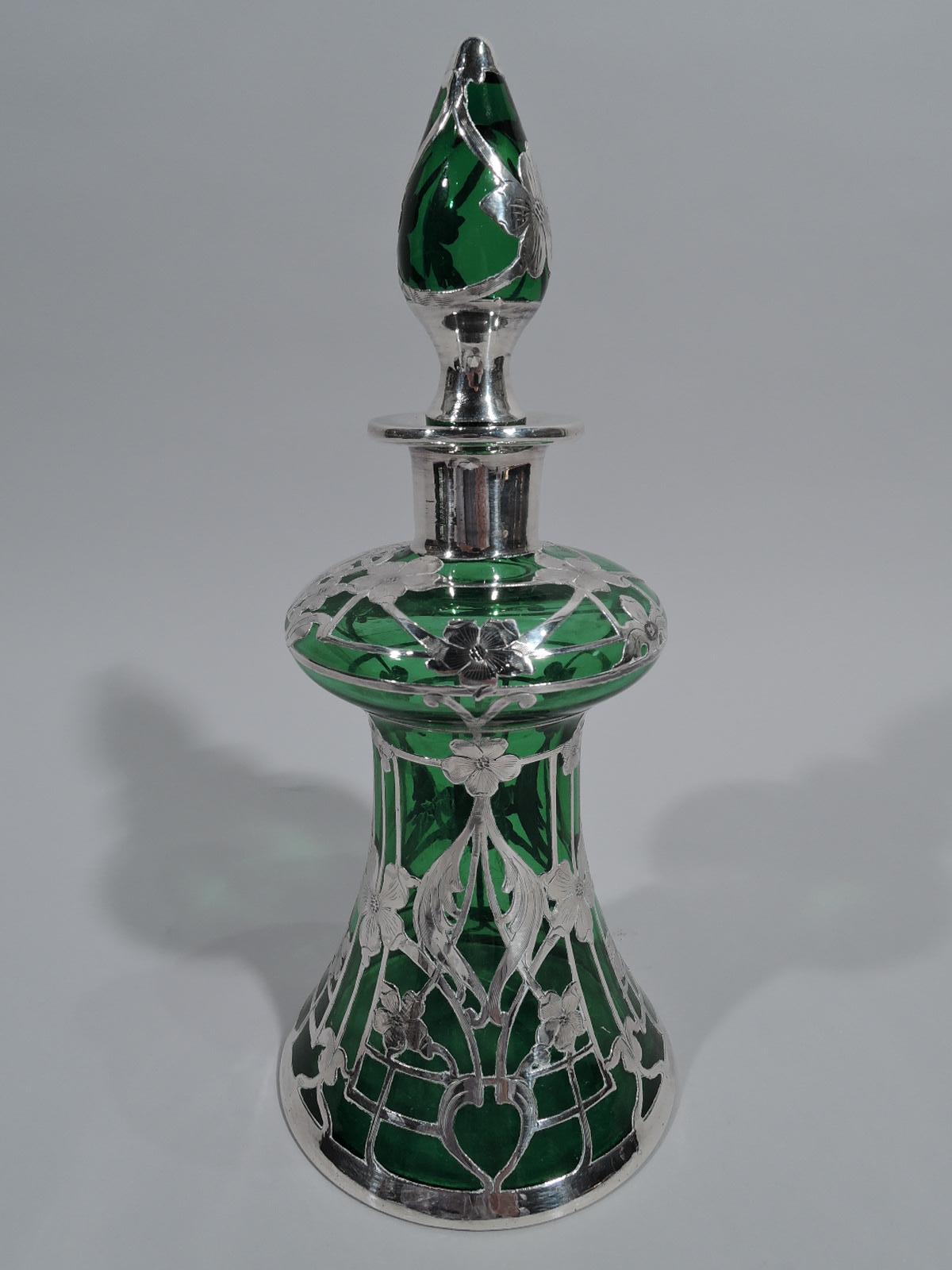 Turn of the century Art Nouveau glass decanter with engraved silver overlay. Unusual form with conical body, bellied top, straight and inset neck, and flat everted rim. Stopper oval. Overlay in form of rectilinear trellis with flower heads and
