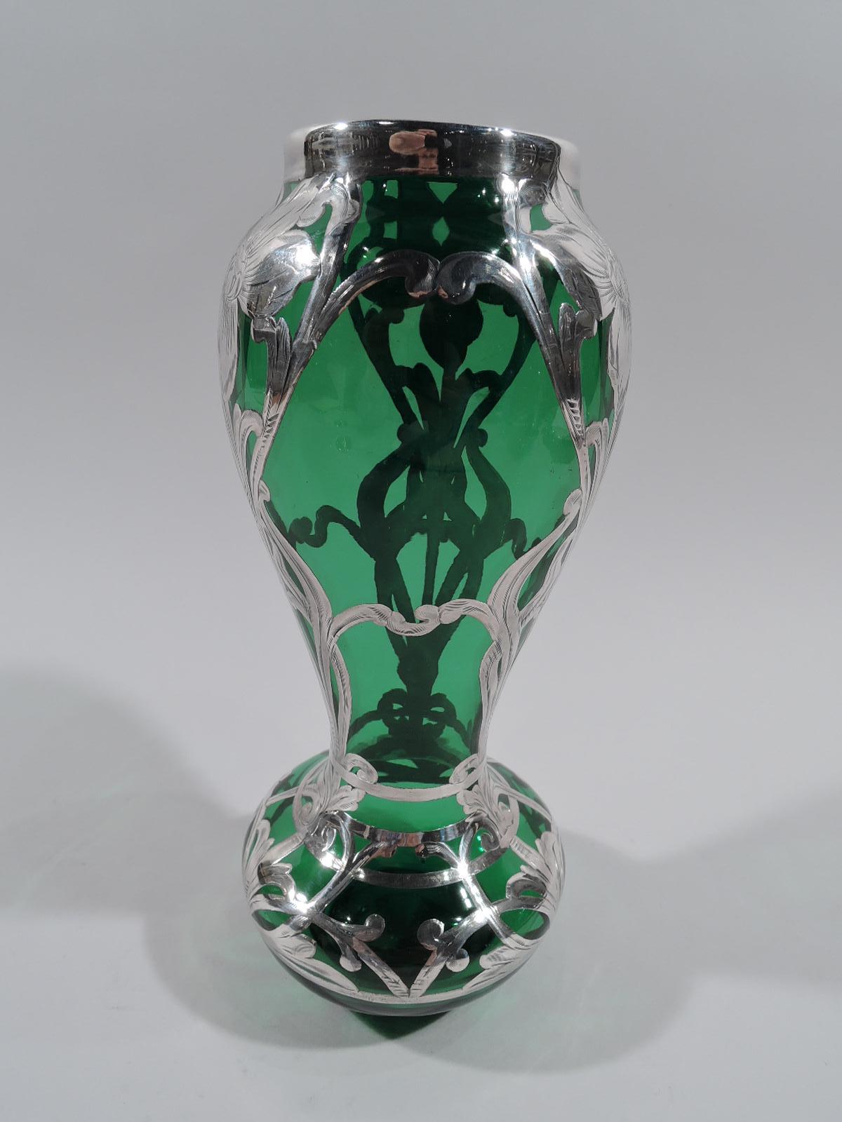 Turn-of-the-century American Art Nouveau glass vase with engraved silver overlay. Voluptuous baluster flowing into bellied bowl; short straight neck in silver collar and plain inset foot ring. Open overlay pattern comprising flowers with interlaced