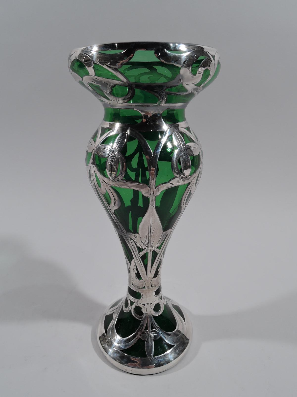Vase en verre Art nouveau du début du siècle, avec un revêtement en argent gravé. Balustre voluptueux s'écoulant dans un pied surélevé et une bouche hémisphérique ventrue. Motif de superposition semi-abstrait centré sur des boutons de fleurs en