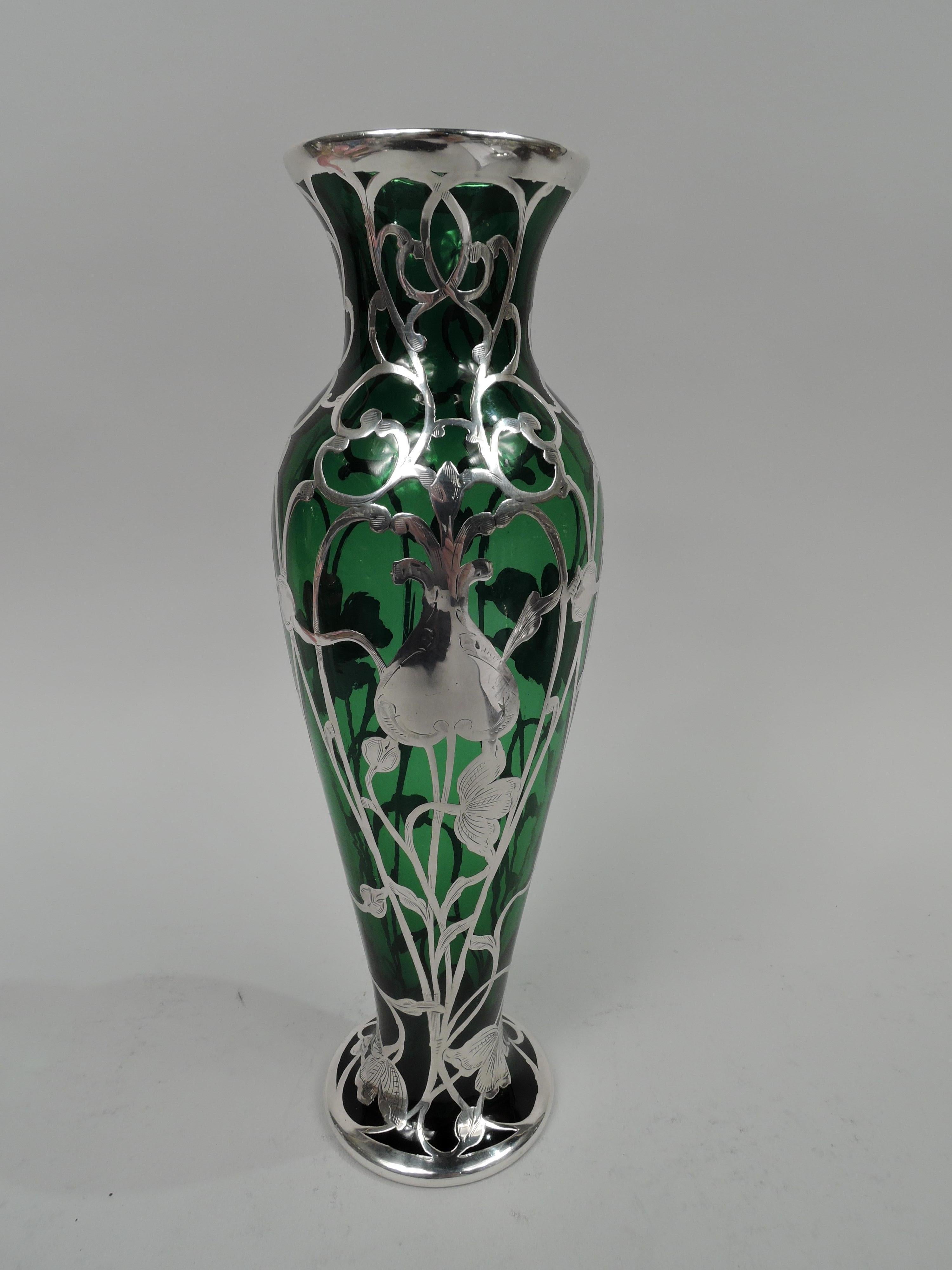 Turn-of-the-century American Art Nouveau glass vase with engraved silver overlay. Ovoid with short inset neck, flared mouth, and spread foot. Loose and open overlay comprising entwined tendrils and flowers from tight buds to splayed flower heads.