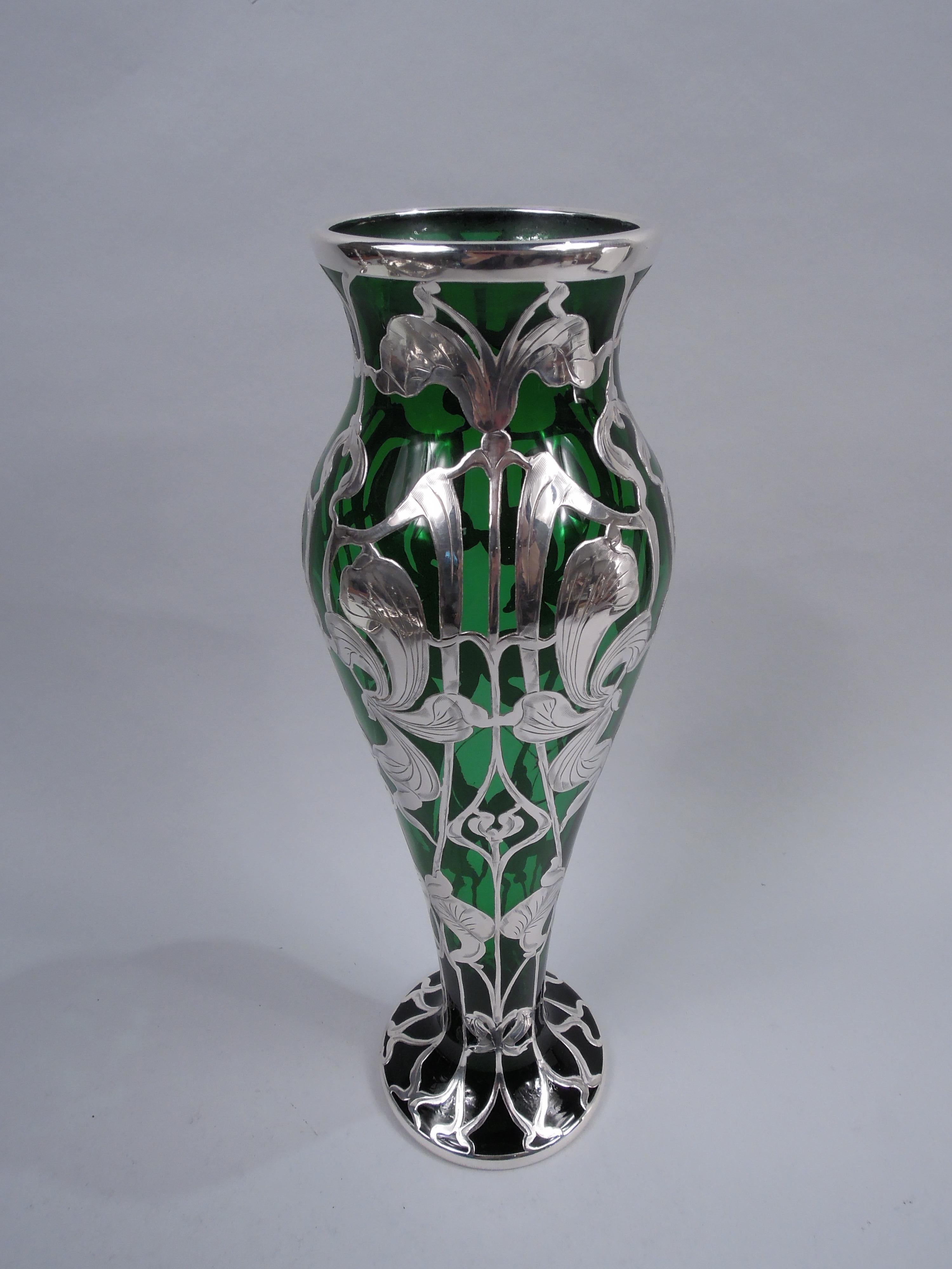 American Art Nouveau glass vase with engraved silver overlay, ca 1900. Baluster with inset and flared rim and spread foot. Vertical overlay pattern comprising distended flower heads and leaves overlapping curvilinear tendrils. Heart-shaped cartouche