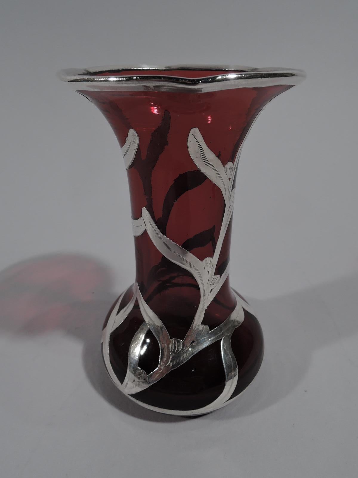 Turn of the century American Art Nouveau glass bud vase with engraved silver overlay. Cylindrical with flared rim and bellied bowl. Semi-abstract overlay in form of budding tendrils. Glass is deep red. Faint mark “Sterling”.