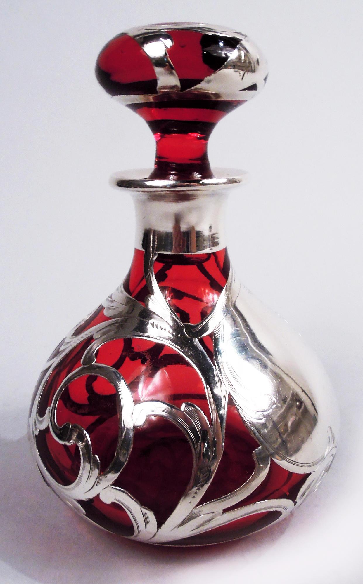 Profumo in vetro Art Nouveau americano con sovrapposizione di argento rosso, 1900 circa. Ovoidale con collo corto e bordo estroflesso in un collare d'argento; tappo a sfera appiattito. Sovrapposizione a forma di viticci e intrecci; grande cartiglio