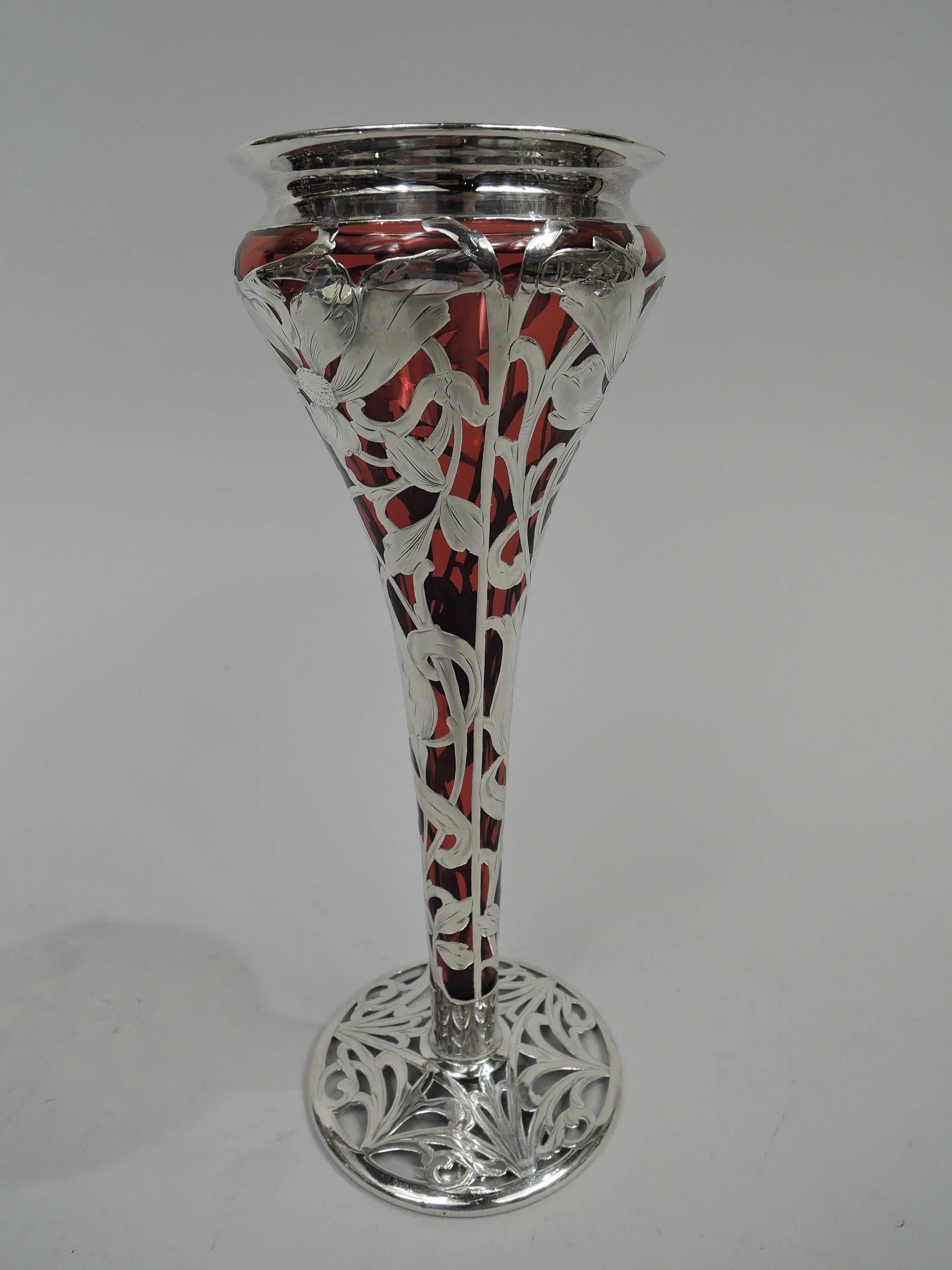 Turn-of-the-century Art Nouveau glass vase with engraved silver overlay. Conical with flared rim and gently raised round foot. Overlay in form of loose and distended flower heads on scrolling and entwined stems; on foot dense tendril pattern. Body