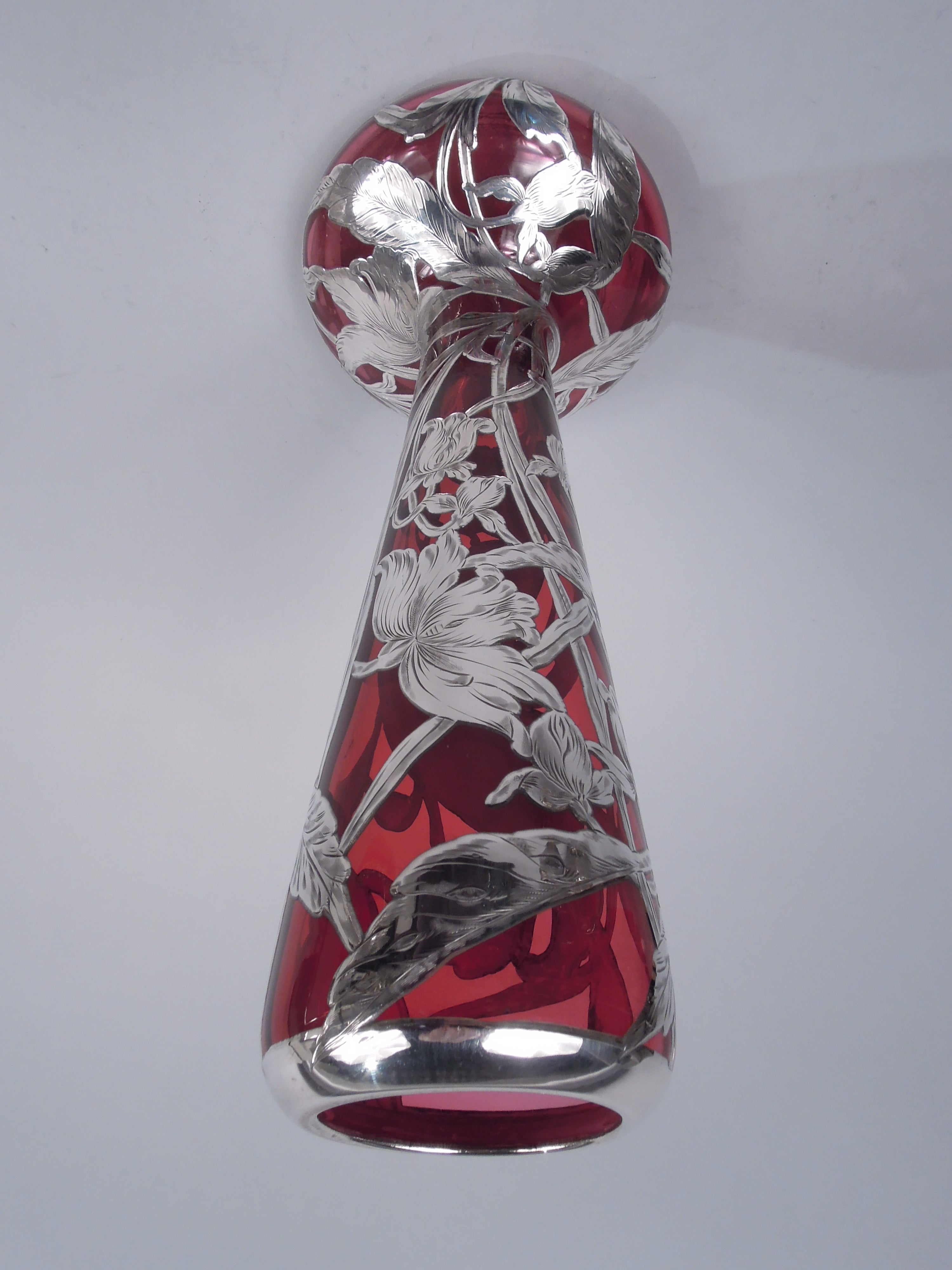 Amerikanische Jugendstil-Glasvase mit graviertem Silberüberfang, um 1900. Hoher und spitz zulaufender Hals mit eingedrehtem Mundrand in Silberkragen. Breite und bauchige Schale. Überlagerung in Form von windgepeitschten Blüten und verschlungenen und