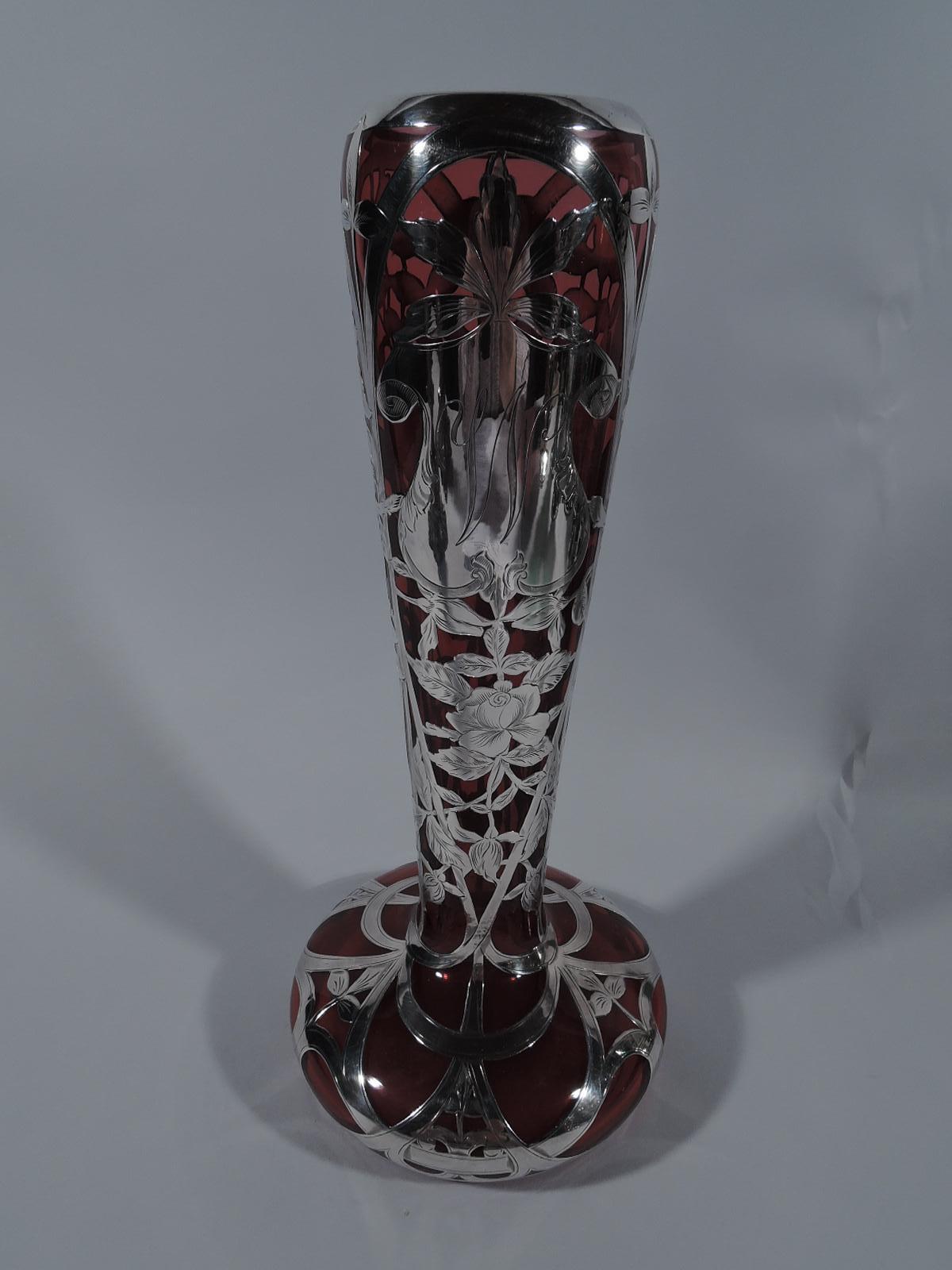 Turn-of-the-century American Art Nouveau red glass vase with silver overlay. Narrow cone and wide and bellied bowl. Engraved overlay in form of flowering rose branch and open scrollwork. Strapwork cartouche engraved with script letter W.