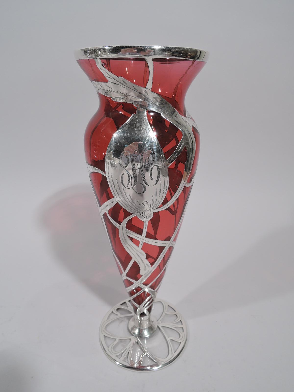 Turn-of-the-century American Art Nouveau glass vase with engraved silver overlay. Ovoid with flat round foot and flared mouth. Floral overlay with splayed and serrated petals and bud (engraved with script monogram); interlaced and whiplash tendrils.