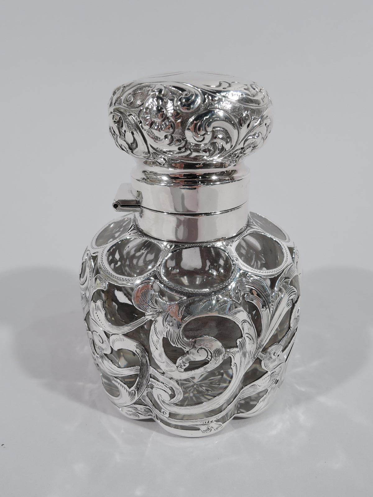 American Art Nouveau clear glass inkwell with silver overlay. Round and lobed with engraved silver overlay in form of whiplash scrolls, leaves, and flowers. Asymmetrical cartouche (vacant). Short neck in silver collar and hinged solid cover with
