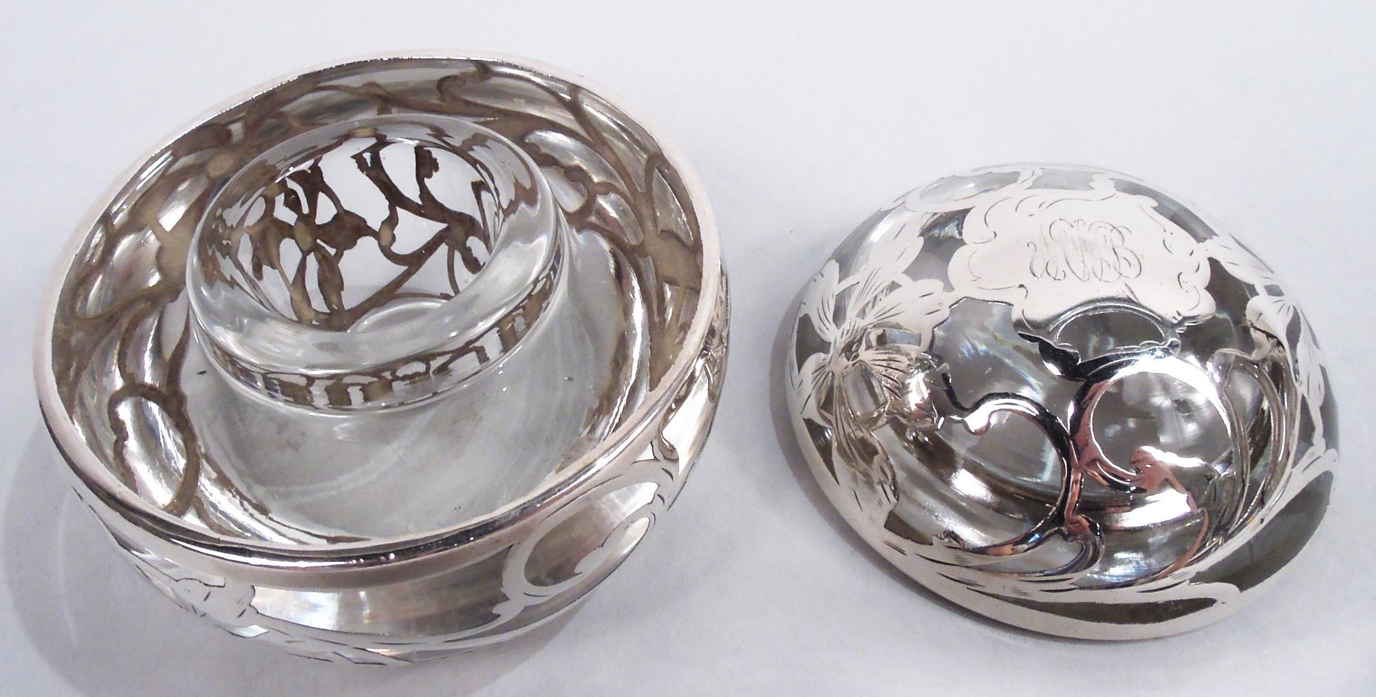 American Art Nouveau glass inkwell with engraved silver overlay, ca 1900. Globular. Bowl has flat top and well with short inset neck and fitted cover. Loose and fluid overlay pattern in form of leafing tendrils and flower heads. On cover top
