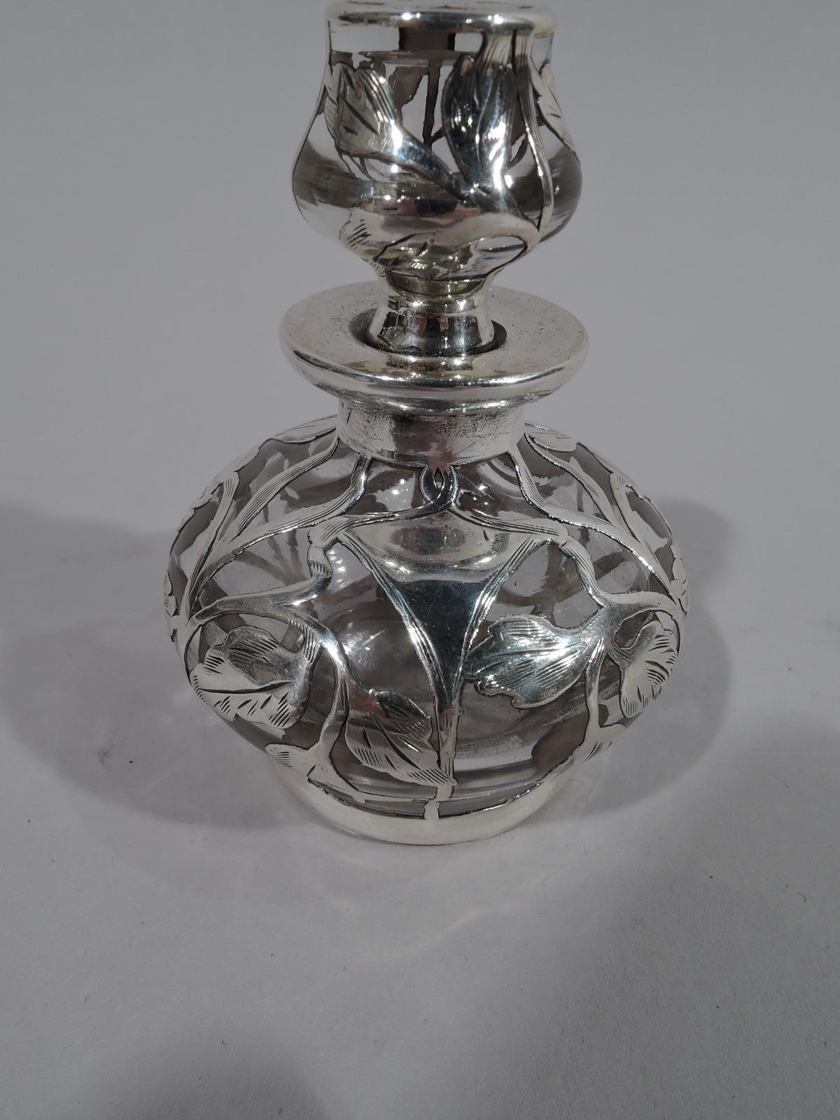 American Art Nouveau clear glass perfume with silver overlay. Made by Matthews in Newark, circa 1910. Bellied bottle with flat rim, and shaped finial with short plug. Engraved overlay with flower heads and leaves joined by tendrils. Loose and fluid.