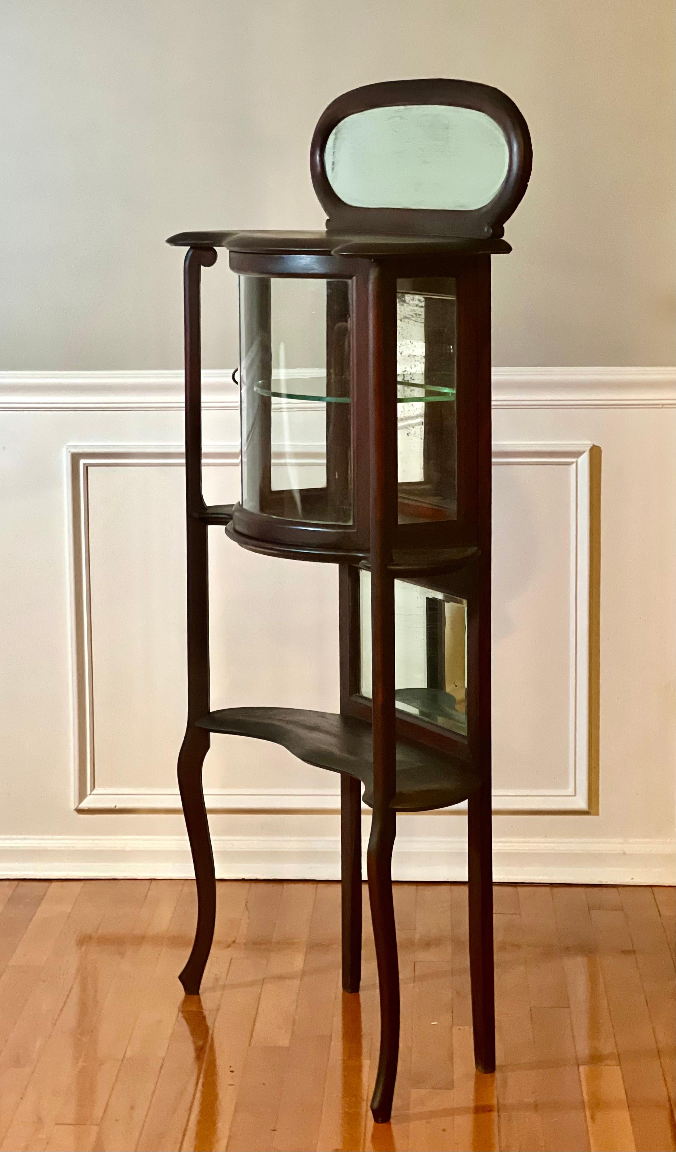 American Art Nouveau étagère with a dark walnut finish, circa 1910's.

A petite étagère with a slim frame suitable for many spaces.  It features beveled mirrors behind beautifully curved, open walnut shelves.  The top mirror has an oval mitered