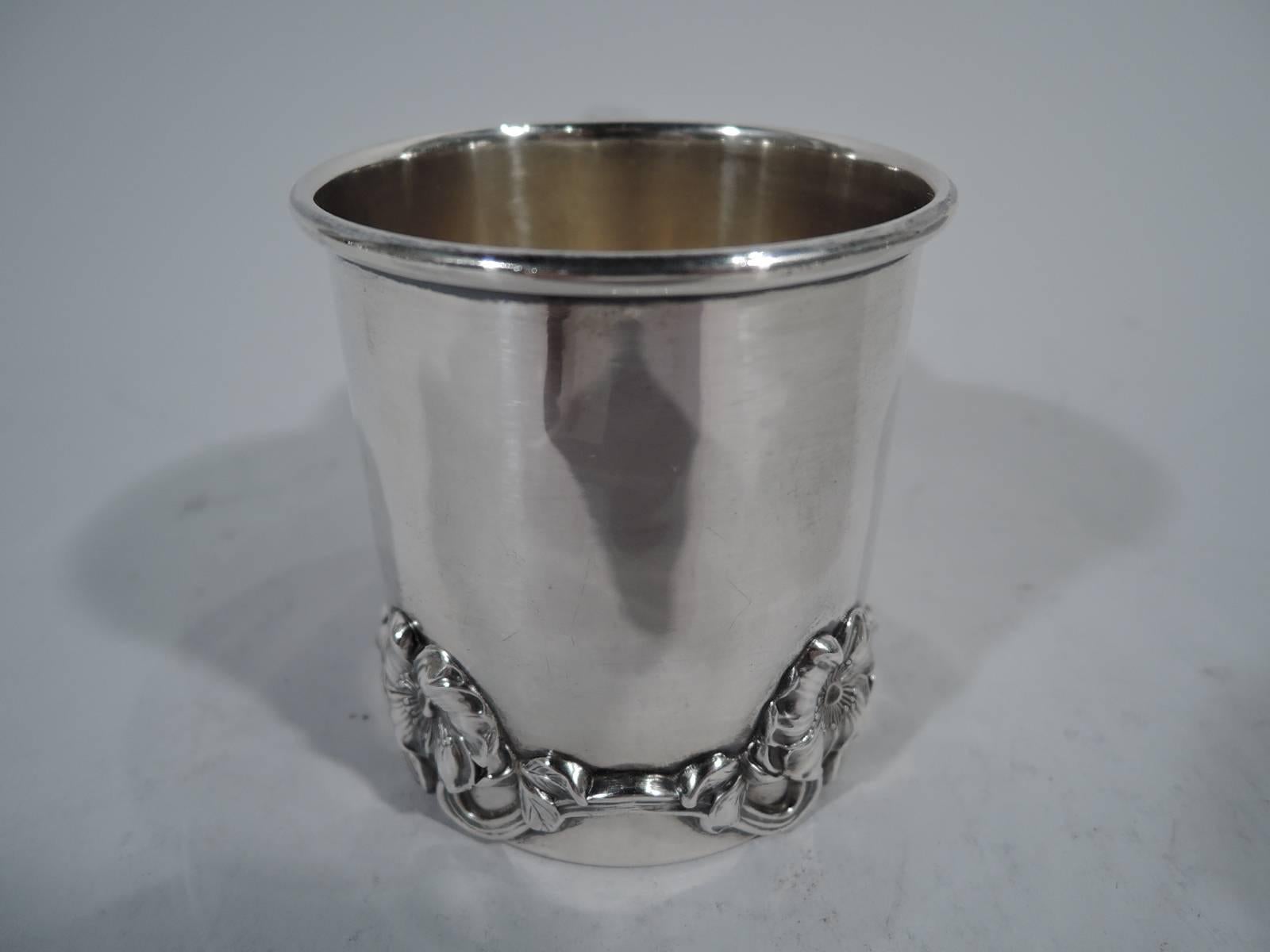 American Art Nouveau sterling silver baby cup. Straight sides and s-scroll handle. Applied flowering branch wraps around base: repeating pattern with pansy-style flower joined by scrolled stems. Fresh and pretty with plenty of room for engraving.