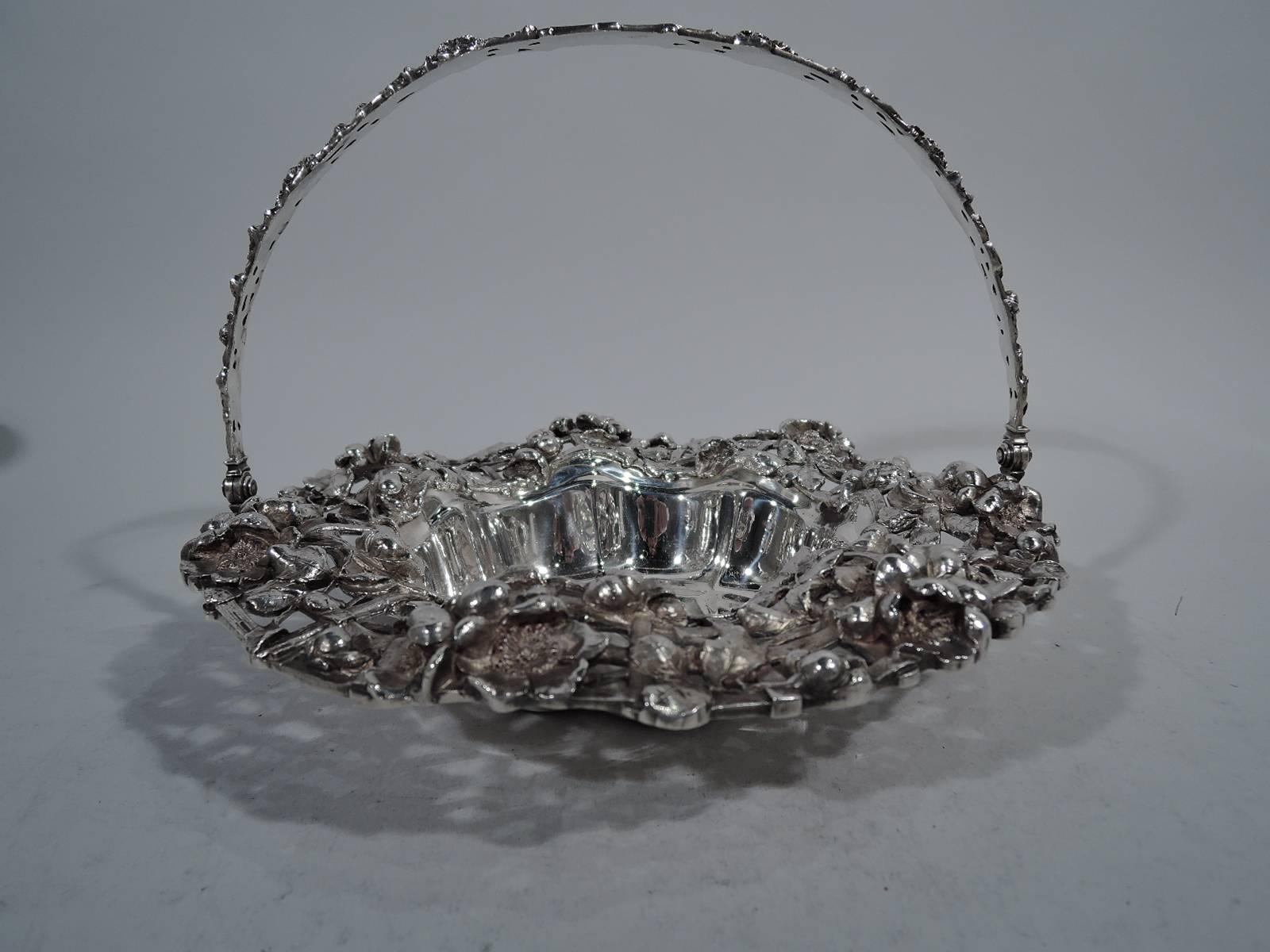 Art Nouveau sterling silver basket. Made by Dominick & Haff in New York in 1902. Plain scalloped well engraved with shaded monogram. Rim wide open trellis interwoven with flowers. C-scroll wing handle same with central oval frame (vacant). Pretty