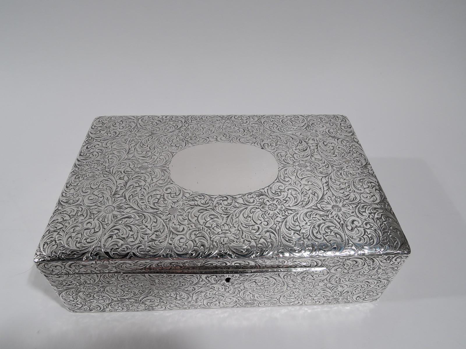 American Art Nouveau sterling silver jewelry box, circa 1910. Rectangular with straight sides. Cover hinged and gently curved with long tab. Dense scrolling flowers engraved allover. Cover top has large oval frame (vacant). Box and cover velvet